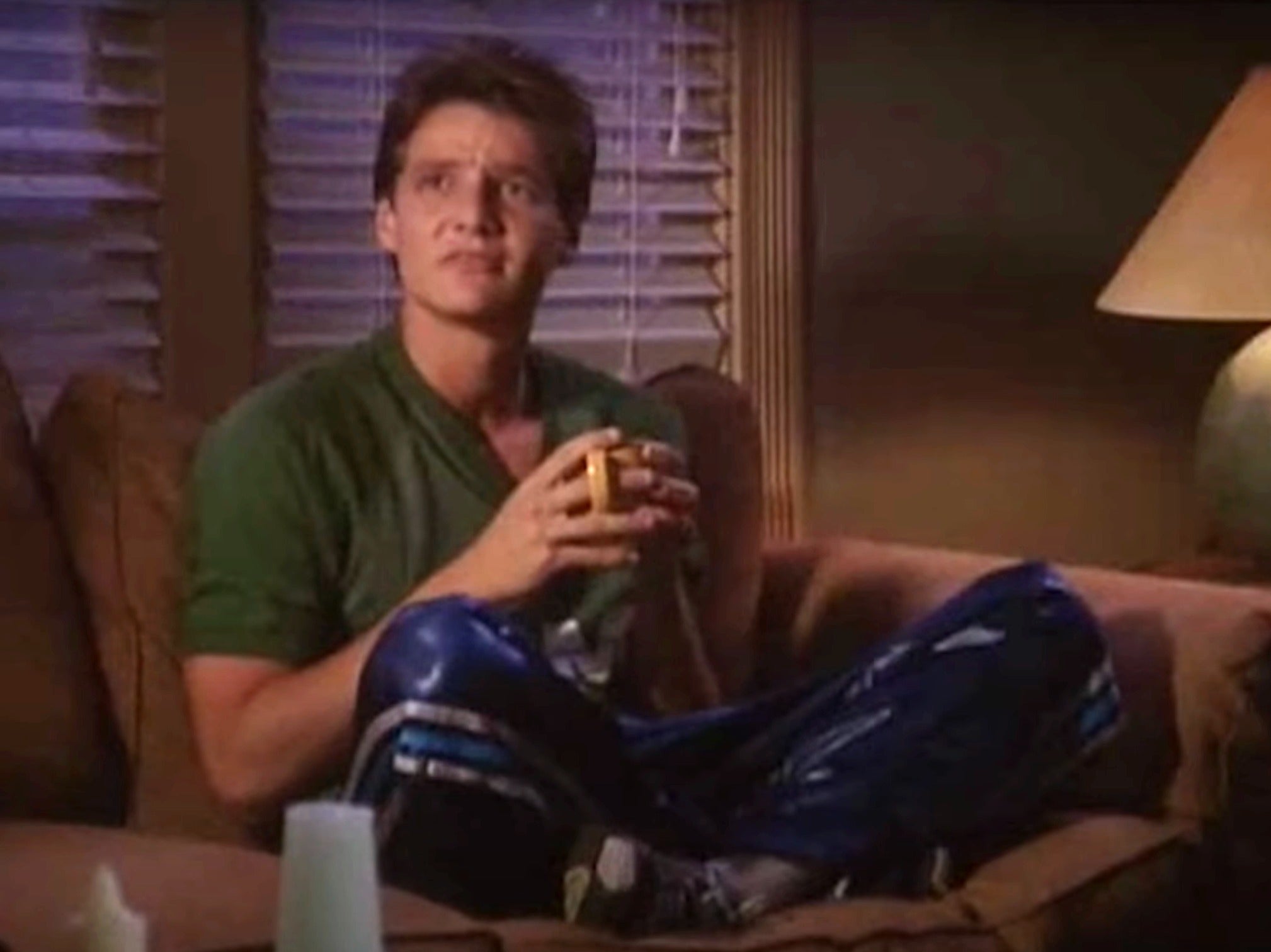 Person in casual clothing, sitting on a couch, holding a mug, looking contemplative