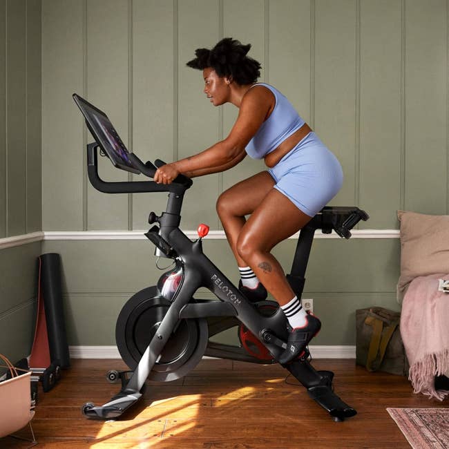 Person successful diversion deterioration utilizing a Peloton motorcycle astatine home, focused connected the screen