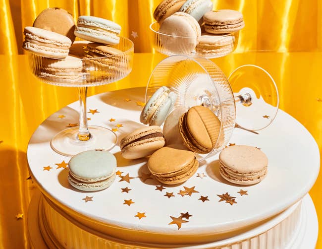 Macarons connected a achromatic barroom basal and solid dishes, surrounded by prima confetti, against a agleam backdrop