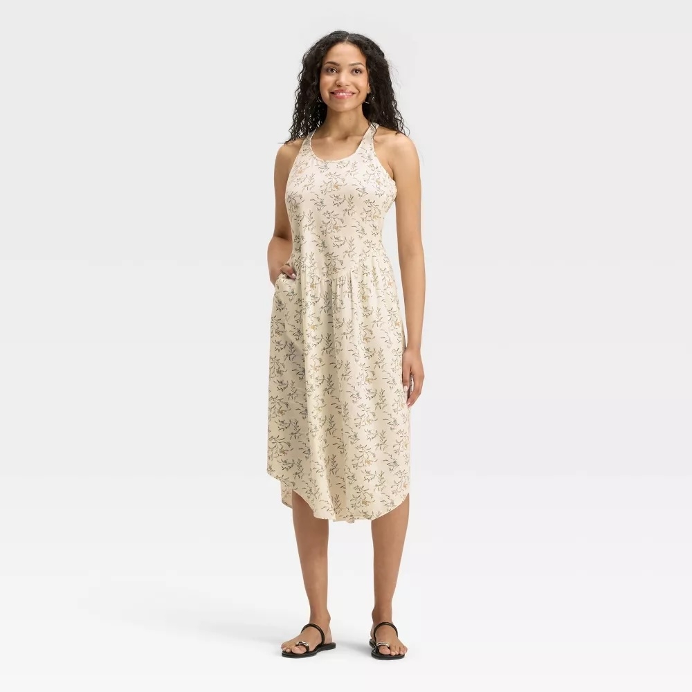 Person wearing a sleeveless floral summer dress with sandals, standing confidently