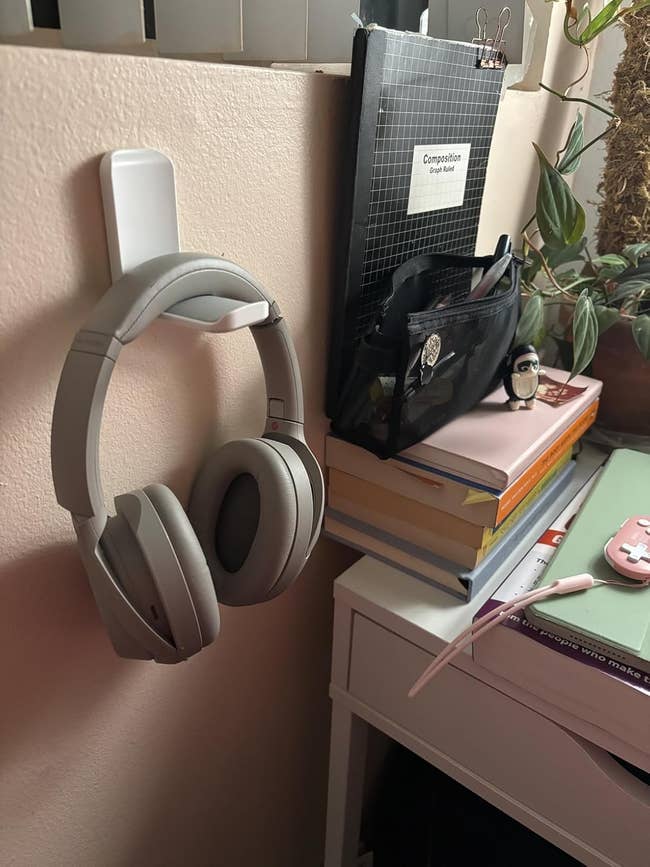 Headphones connected a partition hook, beside a table with a notebook, books, and a plant, suggesting a survey oregon enactment environment