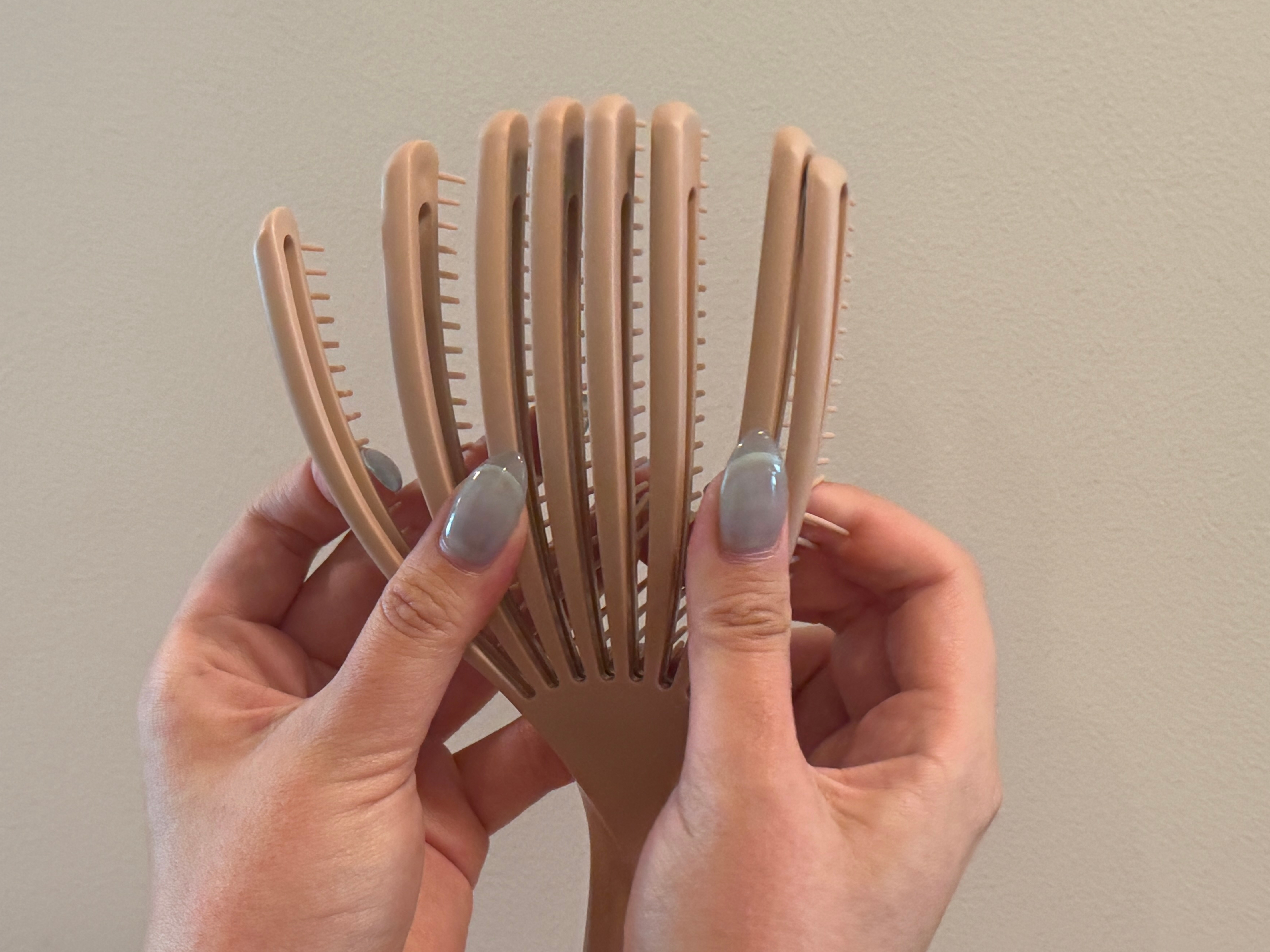 手に持たれている分岐した竹製のヘアブラシ。