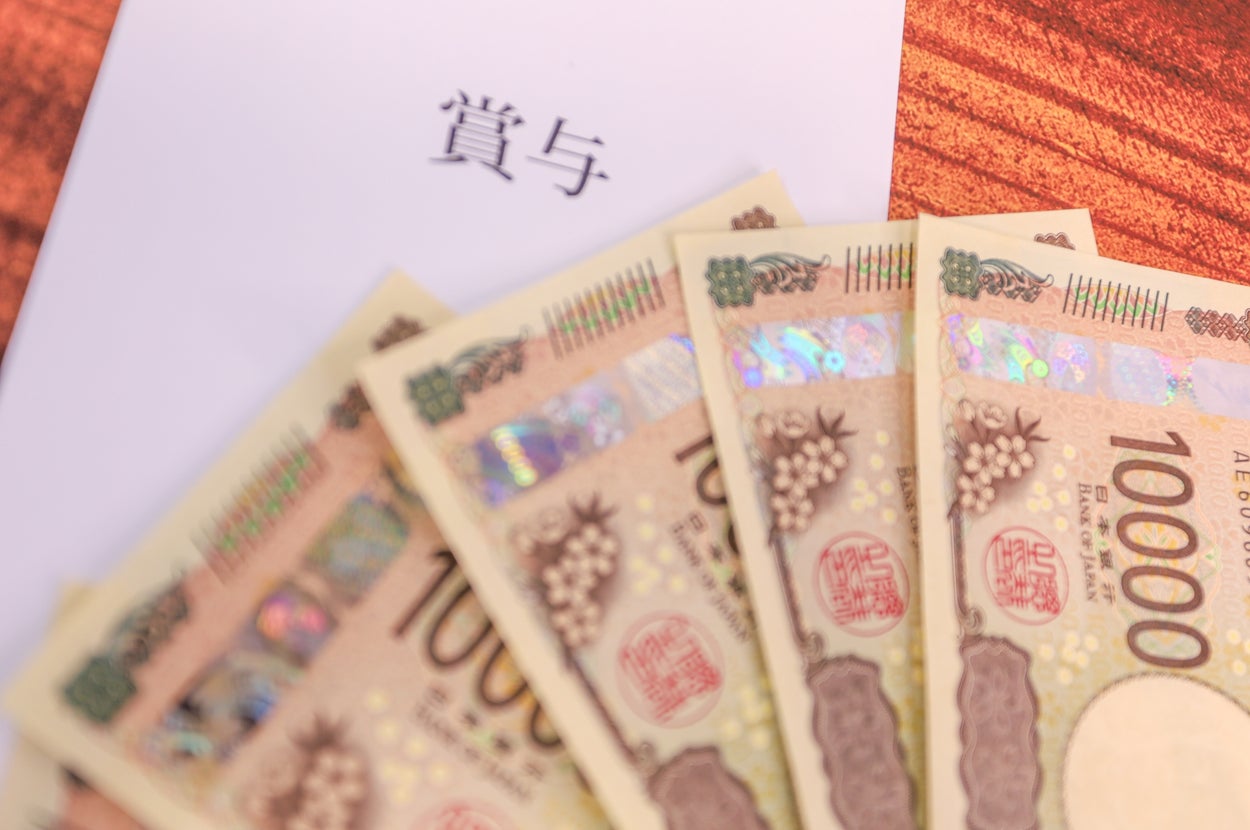 紙に「賞与」と書かれ、10,000円札が数枚重なっている。