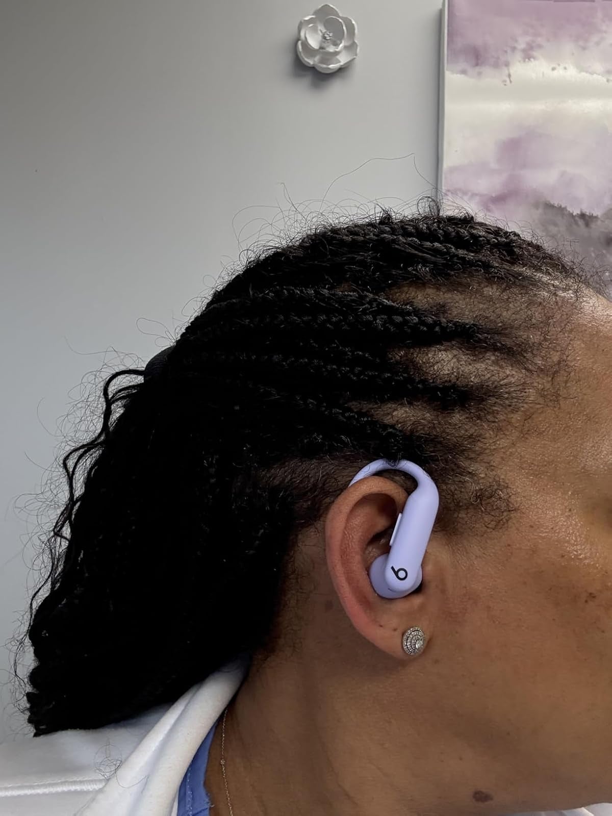 Person wearing wireless earbuds with braided hairstyle, showcasing modern   tech accessory