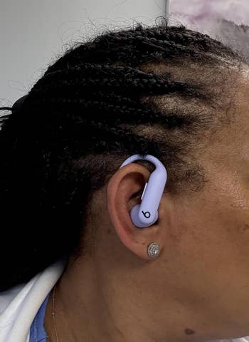 Person wearing wireless earbuds with braided hairstyle, showcasing modern tech accessory