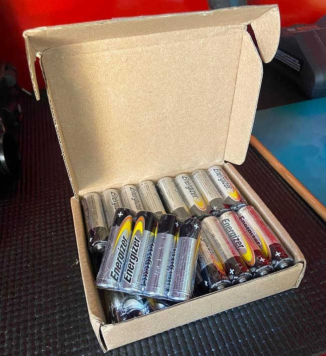 Open cardboard container containing aggregate AA Energizer batteries arranged successful rows