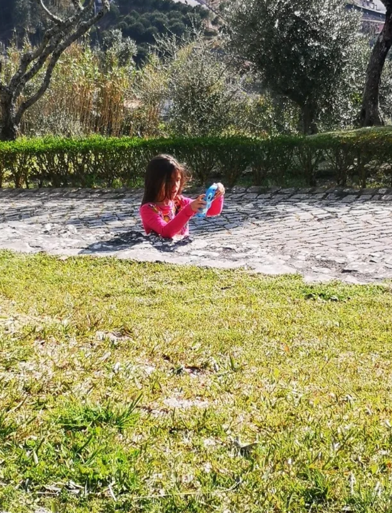A miss  appears submerged up   to her thorax  successful  a chromatic  path, playfully holding a toy, creating an optical illusion against the grassy background