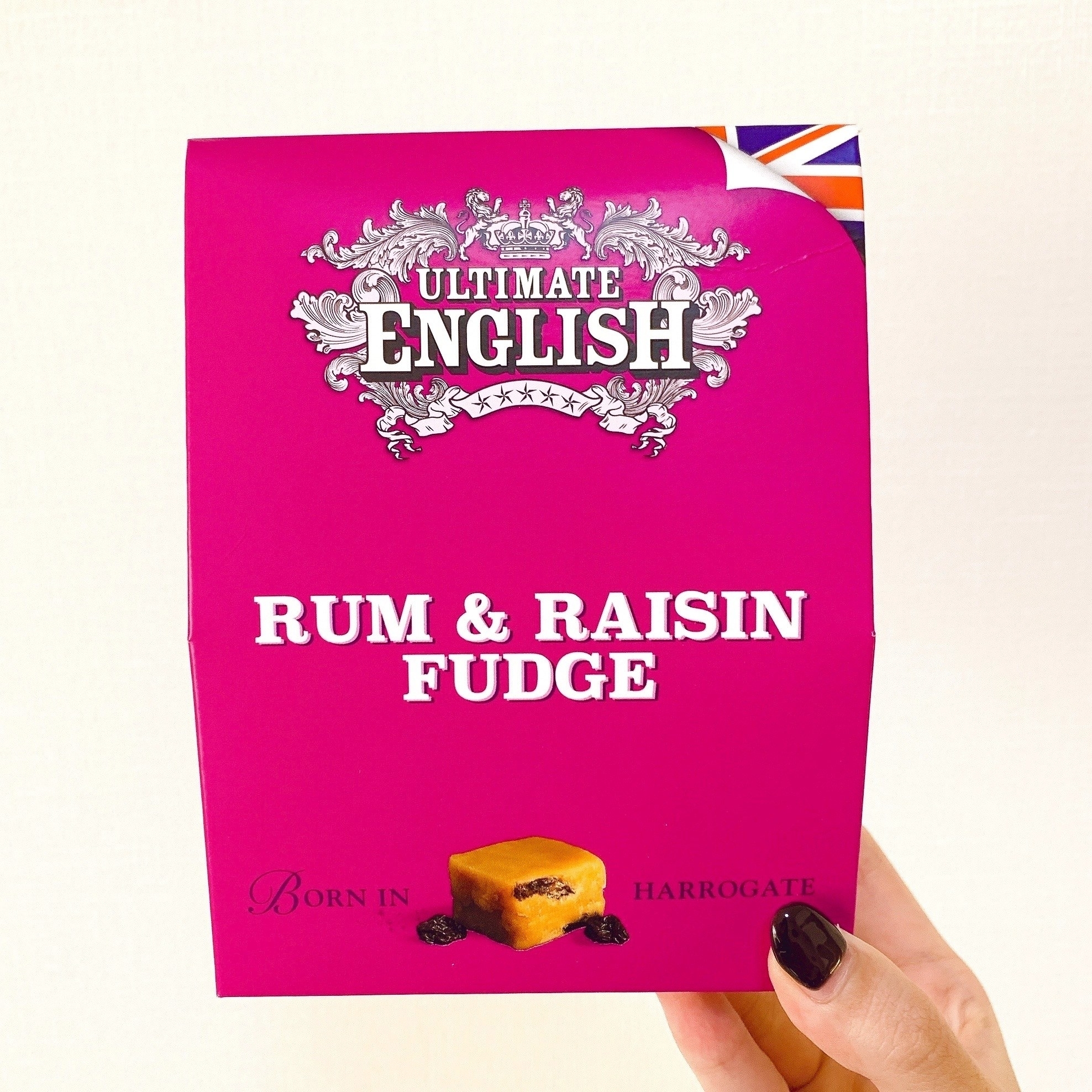 手に持たれた「Ultimate English」ブランドのラムレーズンファッジのパッケージ。