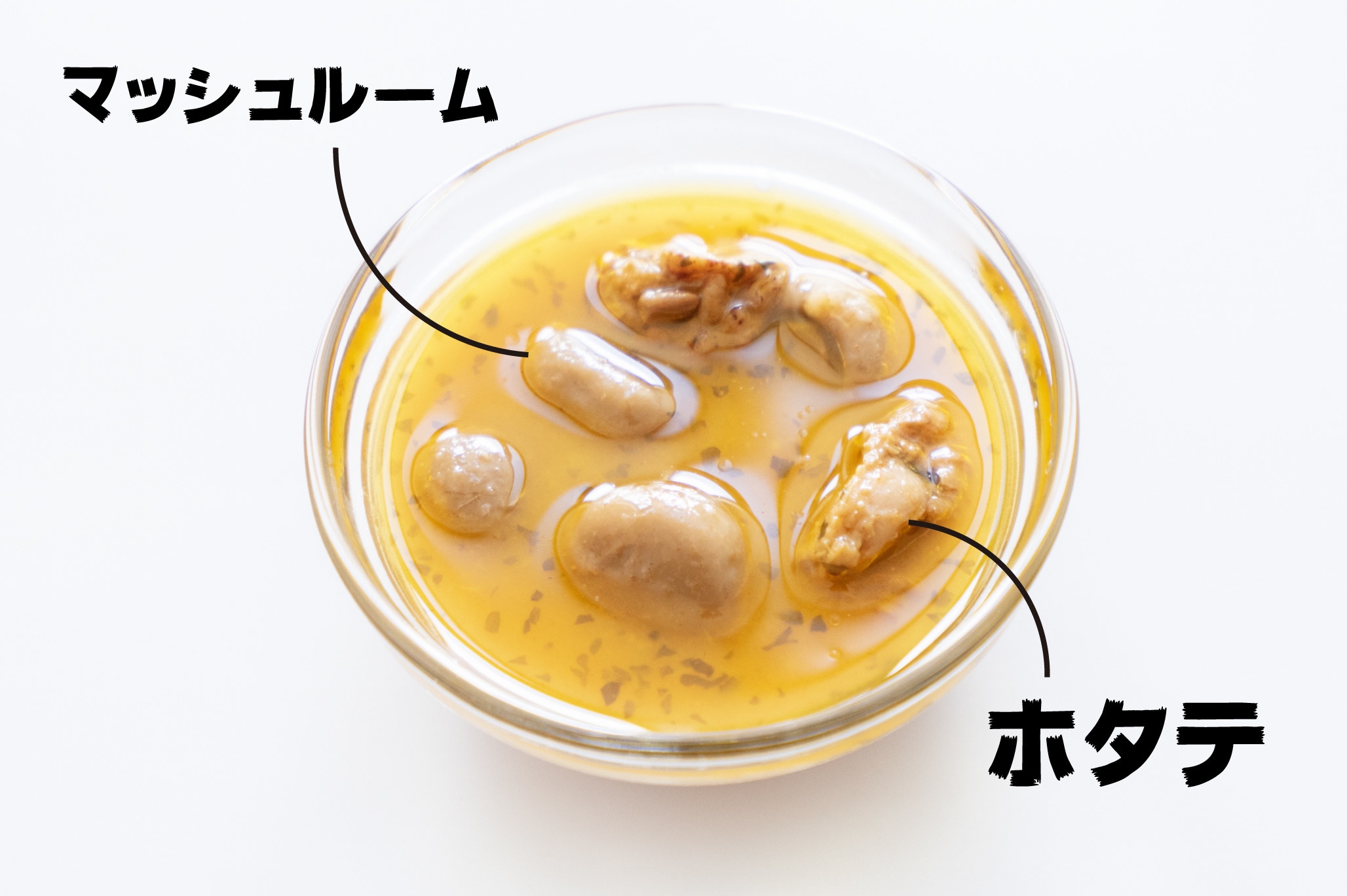 ガラスの器に入ったクリームスープに、マッシュルームとホタテのラベルが付いている。