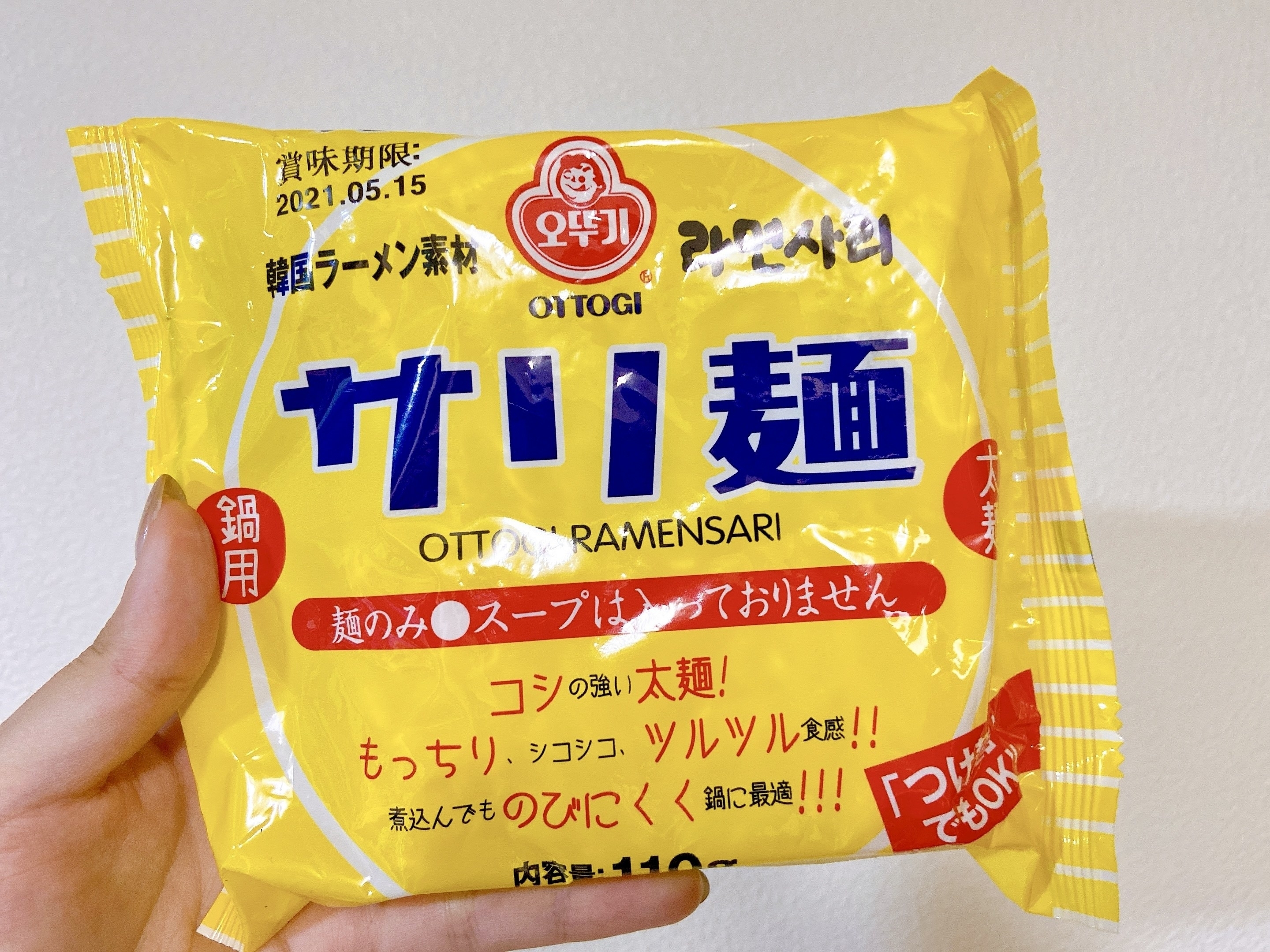 手に持った袋麺パッケージ。韓国のラーメン素、賞味期限:2021年5月15日。内容量110gと記載。