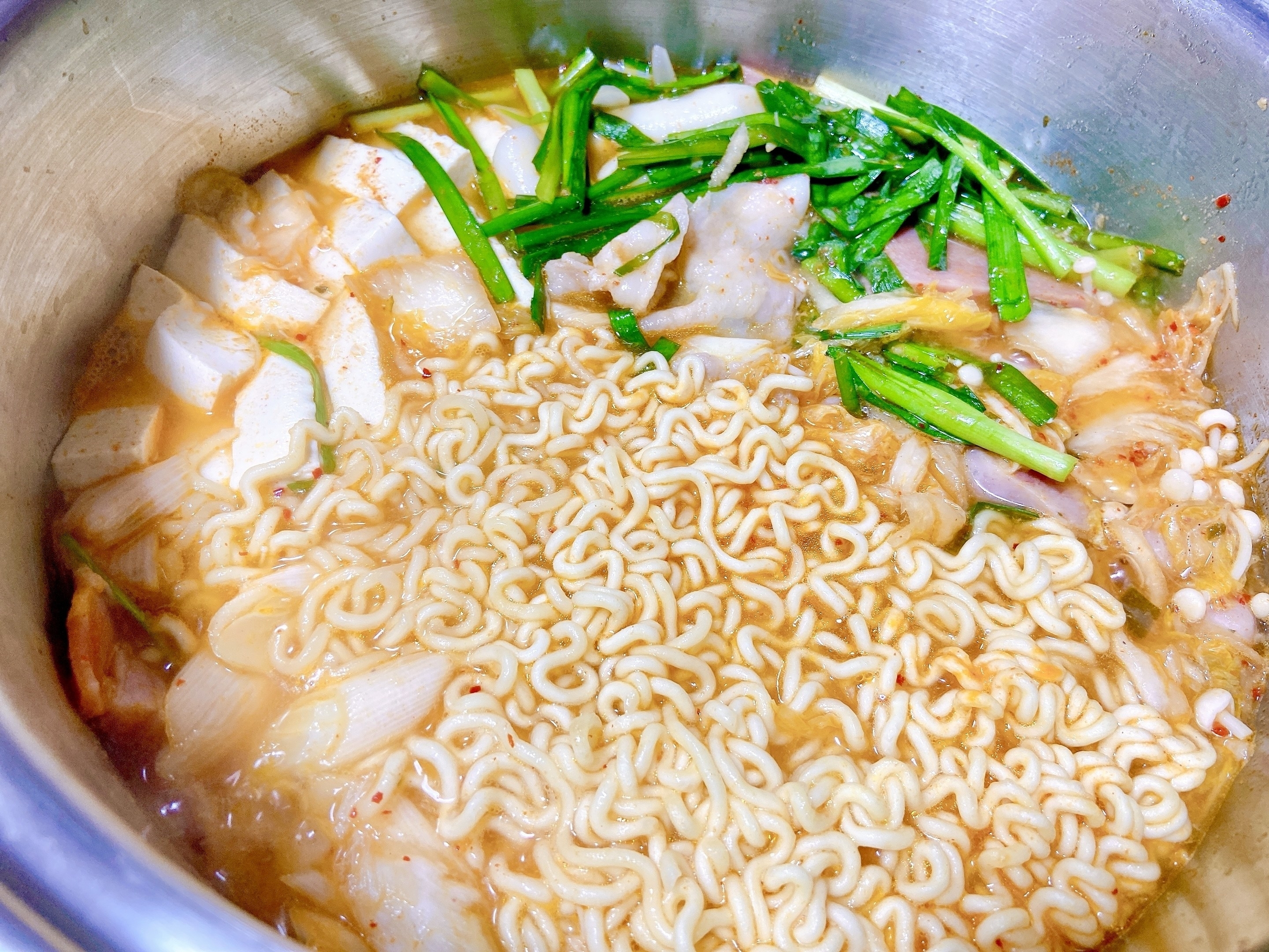 鍋に入った即席麺。キャベツやネギが添えられた料理。
