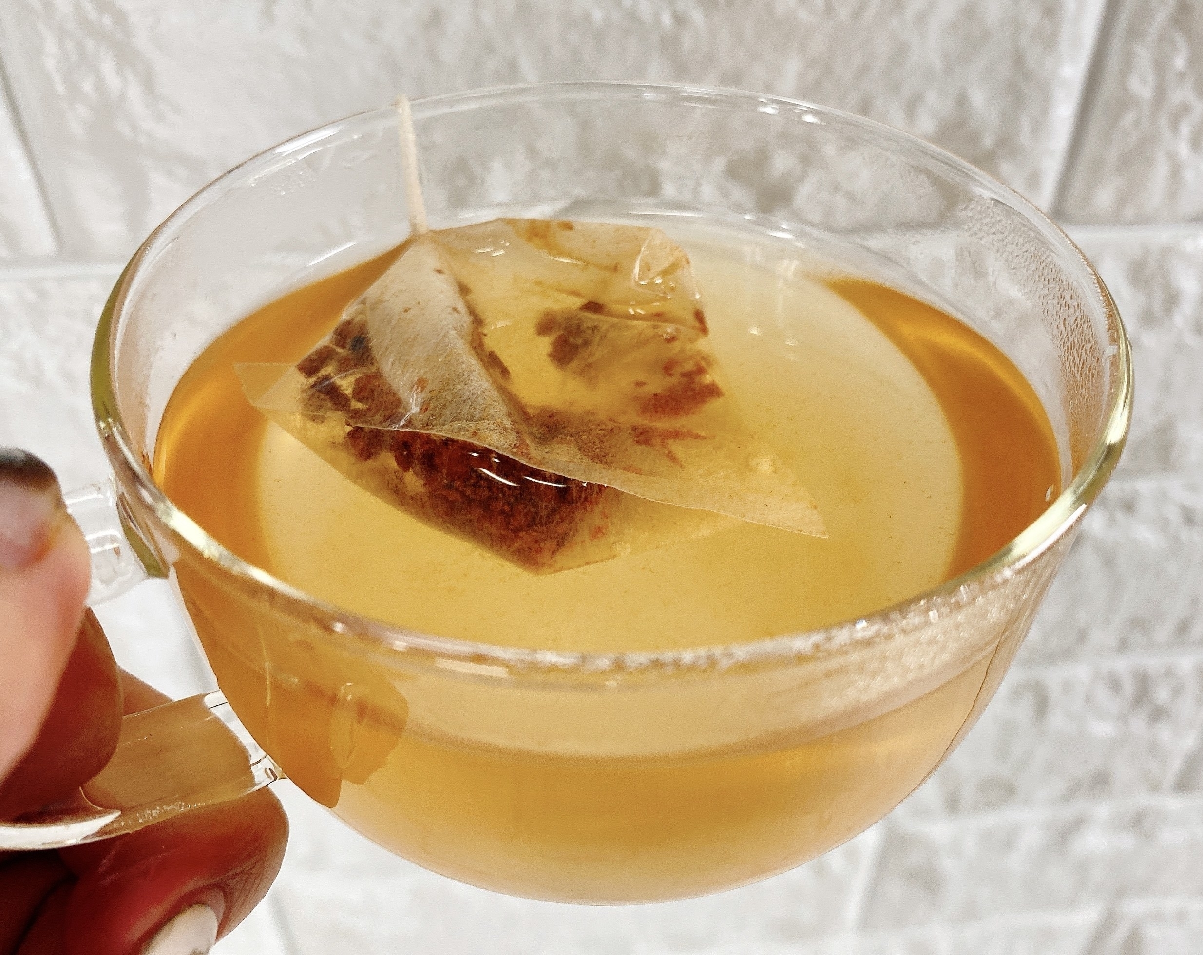 透明なカップに注がれたお茶と浮かぶティーバッグ。
