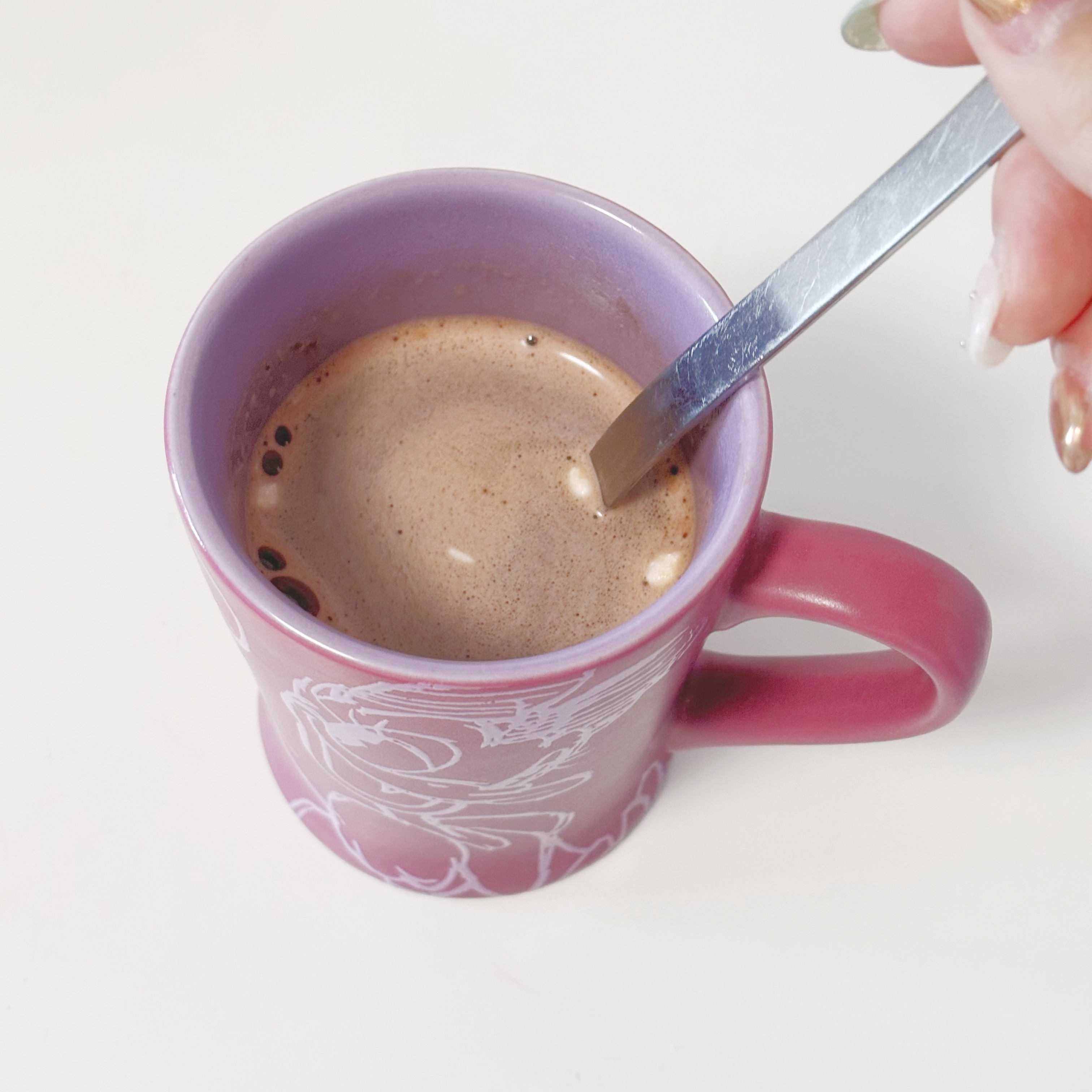 スプーンでかき混ぜられているホットチョコレートが入ったマグカップ。
