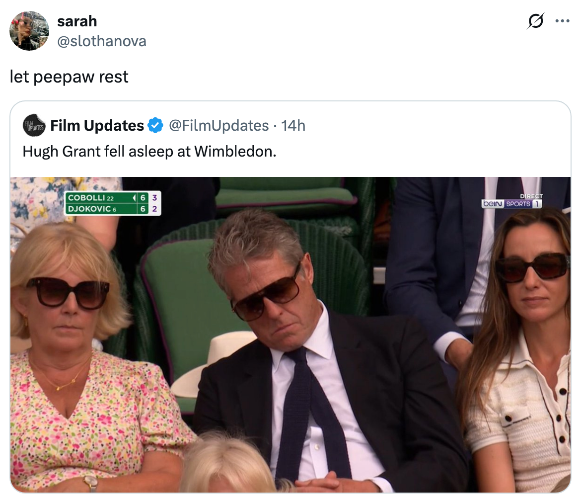 Three people, including a sleeping man in a suit, sit in a stadium. A scoreboard shows a tennis match in progress