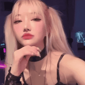 Person posing indoors with long hair and a choker, wearing a sleeveless top