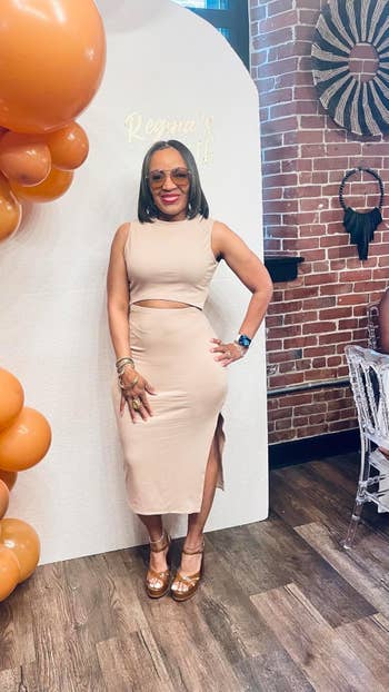 Person successful sleeveless formal poses confidently beside a balloon display, acceptable against a ceramic wall