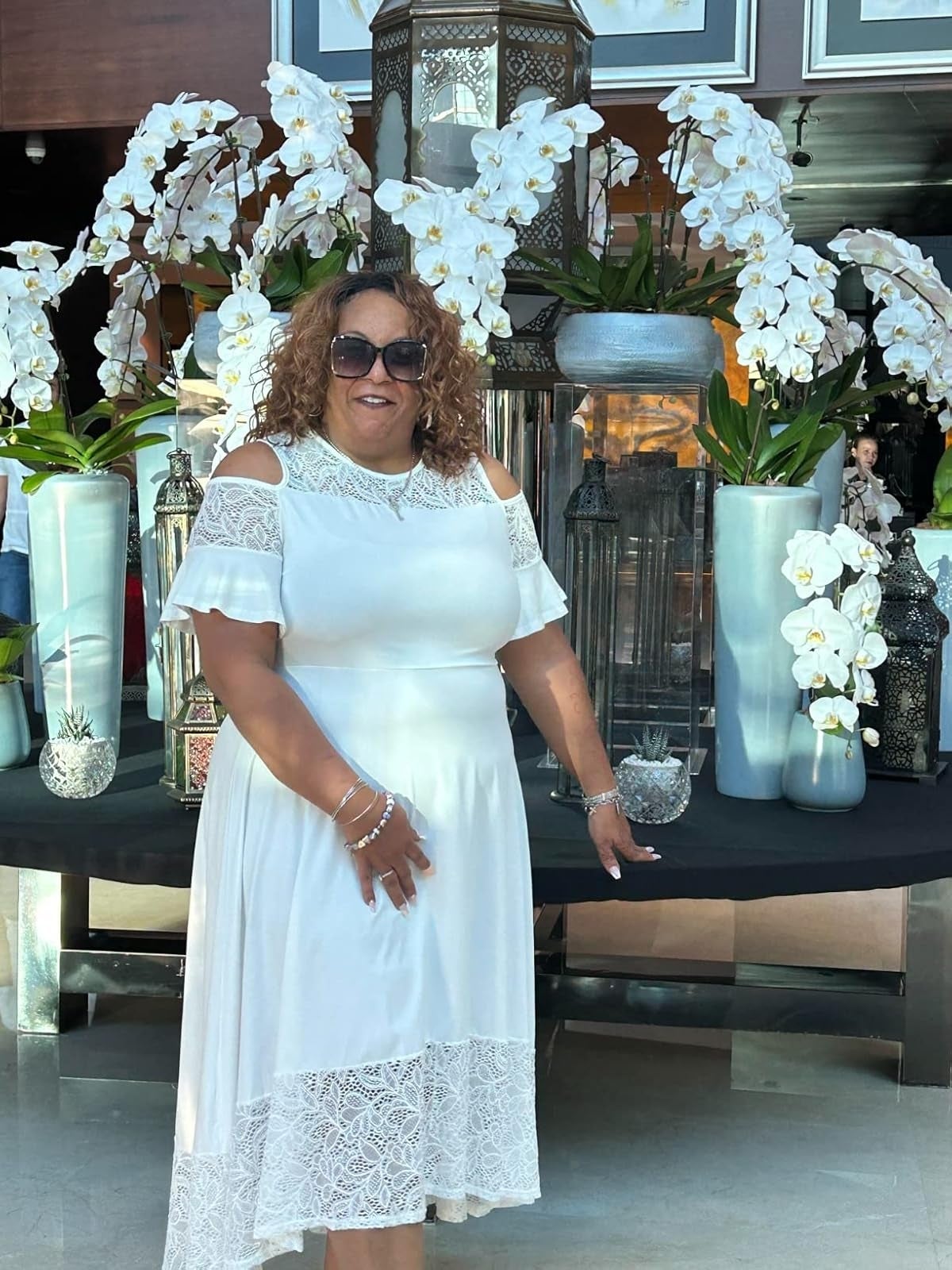 A pistillate   successful  a achromatic  lace formal  poses with vases of orchids