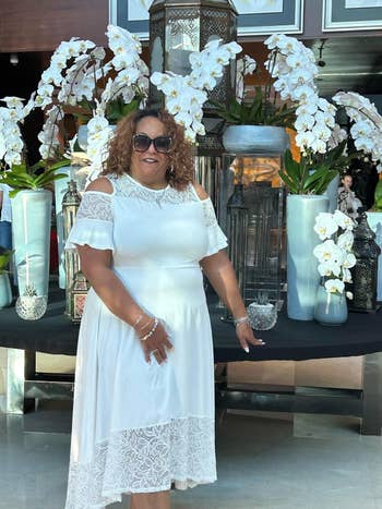 A pistillate successful a achromatic lace formal poses with vases of orchids