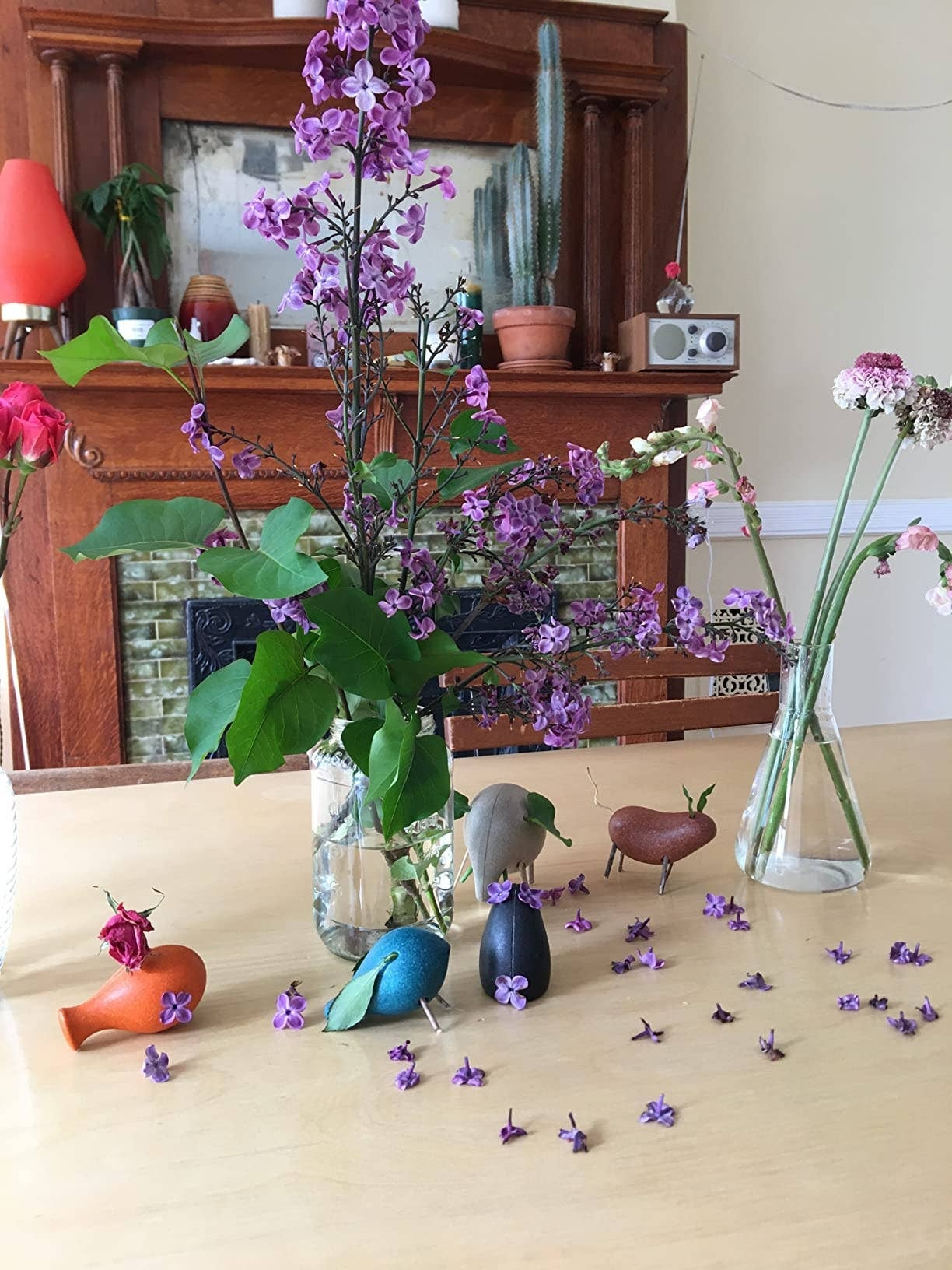 Wooden vertebrate  figurines and tiny  vases of flowers are arranged connected  a array  successful  beforehand   of a decorated fireplace