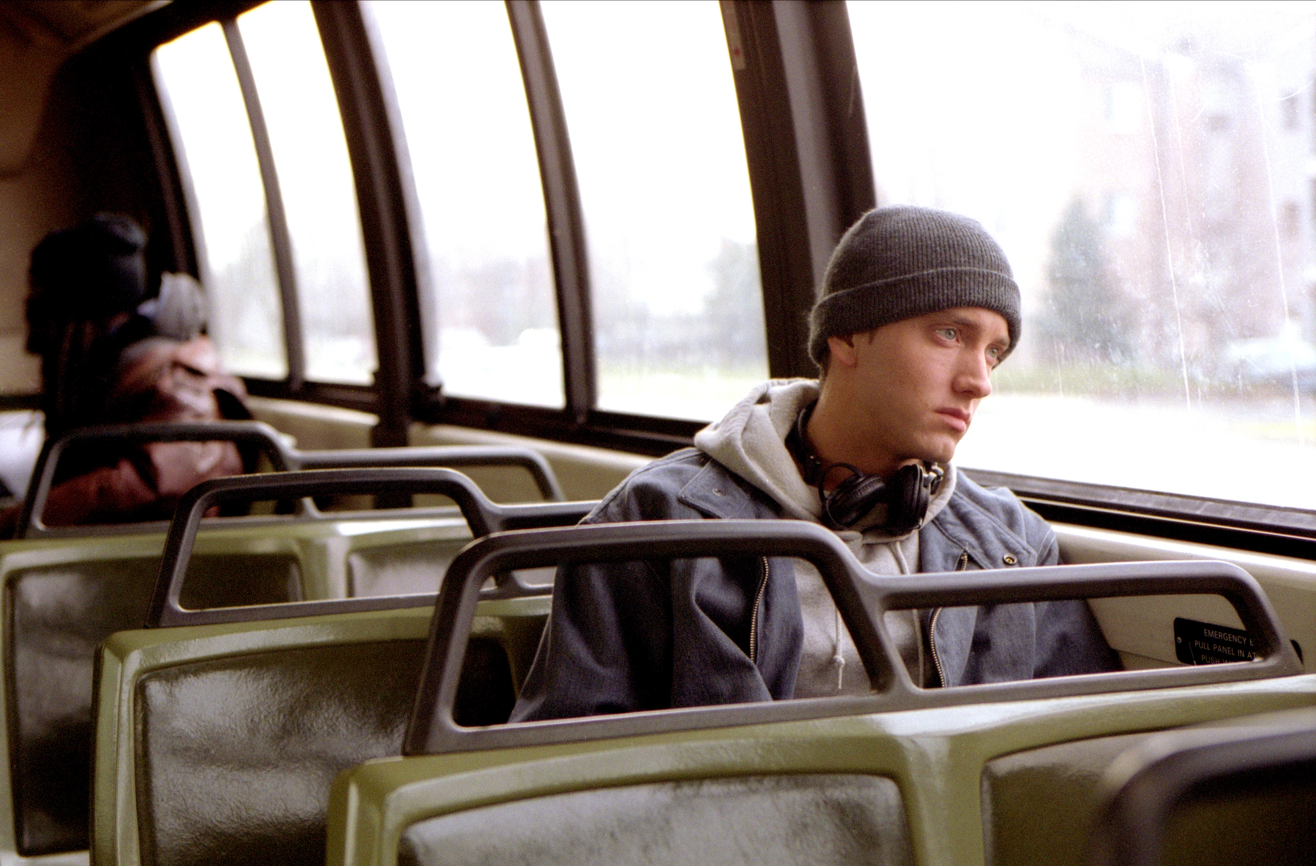 Person in a winter hat, sitting alone on a bus, gazing out the window in thought