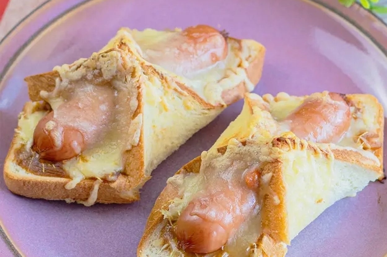 3枚のパンに挟まれたソーセージとチーズを載せた料理が皿に盛られている。