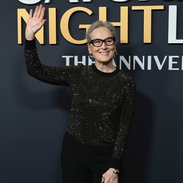 Person in elegant, glittery black top and black pants waves at a "Saturday Night Live" anniversary event