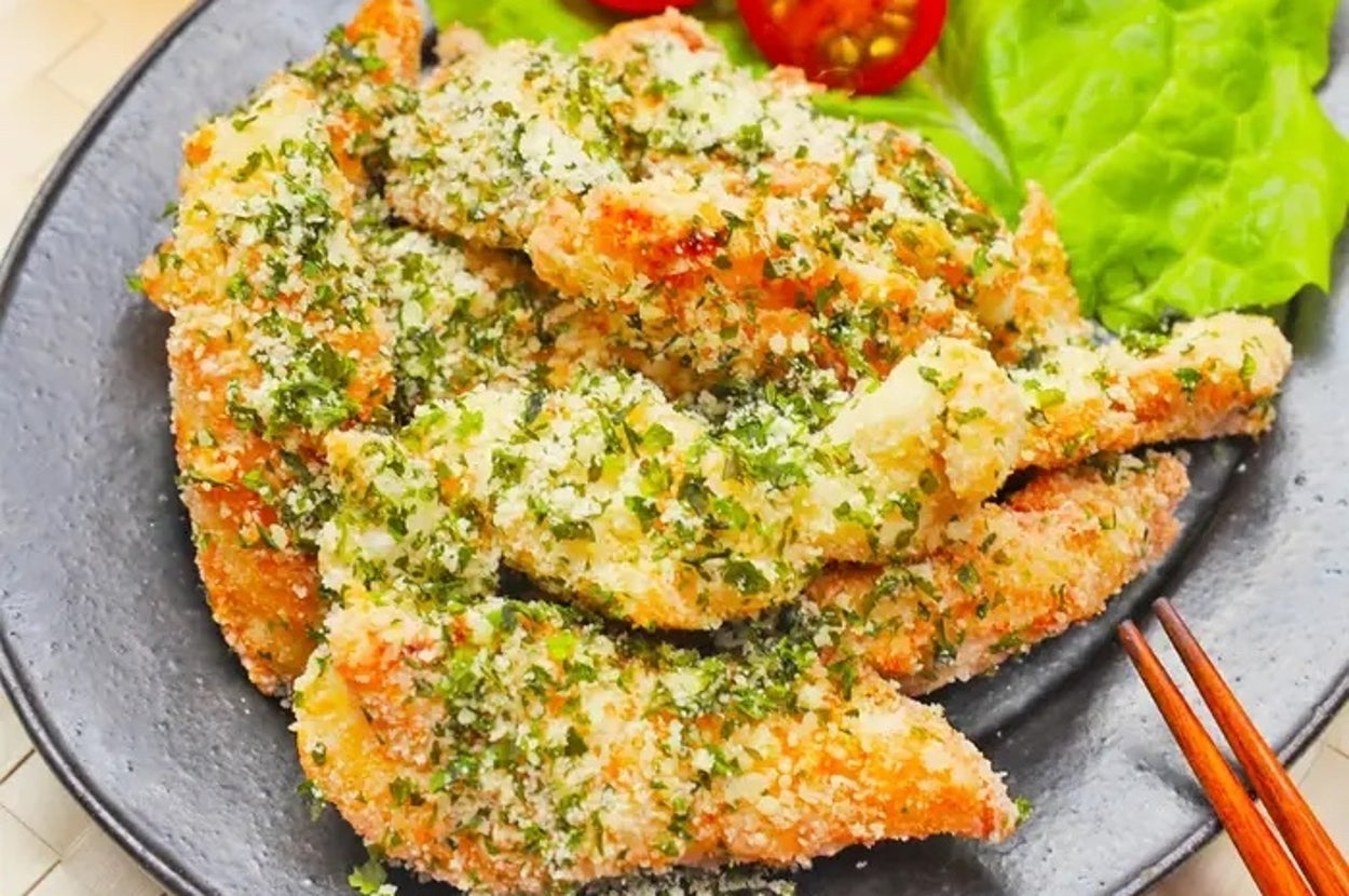 パン粉をまとった鶏むね肉がレタスとトマトと一緒に皿に盛られている。レモンのスライスが添えられている。