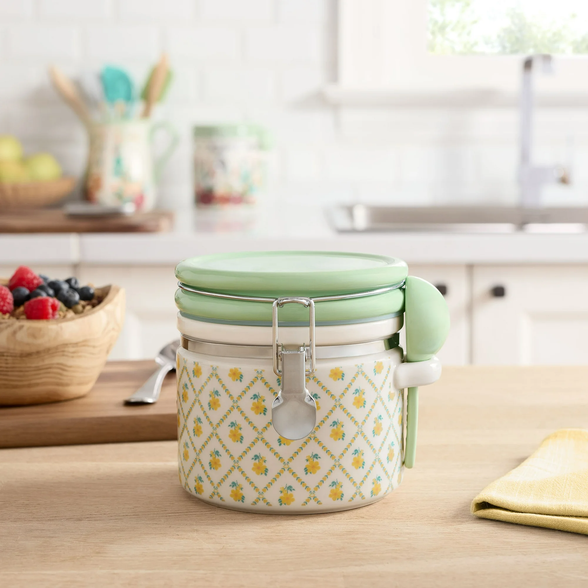 Stackable ceramic canister with a floral pattern is shown on a kitchen counter; it's displayed with a wooden bowl of berries and utensils
