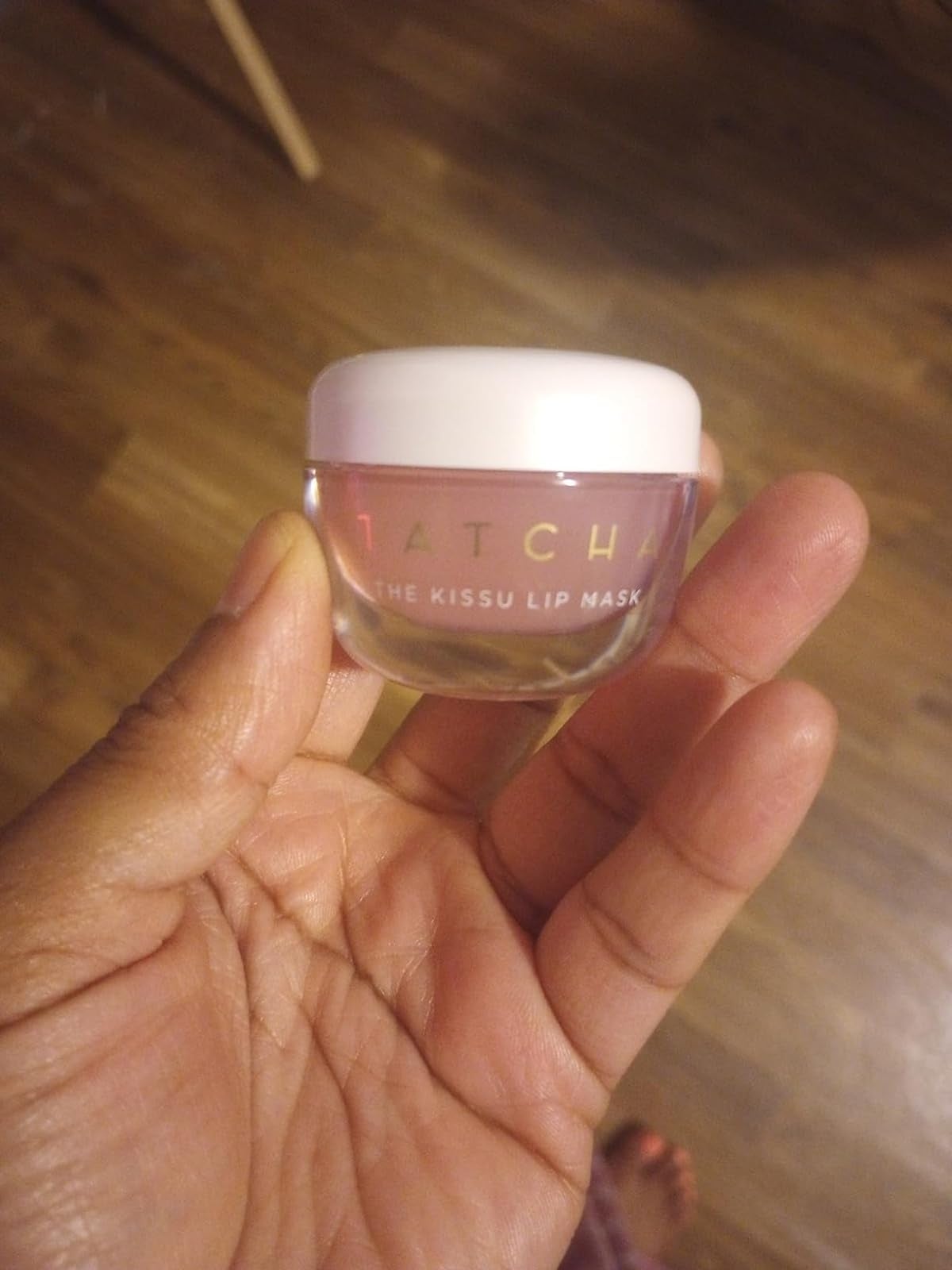 Hand holding a tiny  jar labeled Tatcha The Kissu Lip Mask