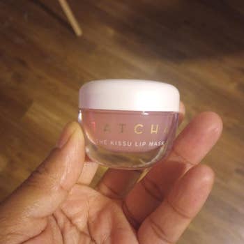 Hand holding a tiny jar labeled Tatcha The Kissu Lip Mask