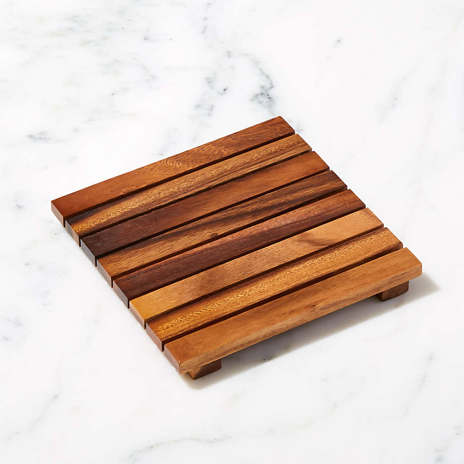 Wooden trivet with parallel slats on a marble surface, suitable for protecting surfaces from hot cookware
