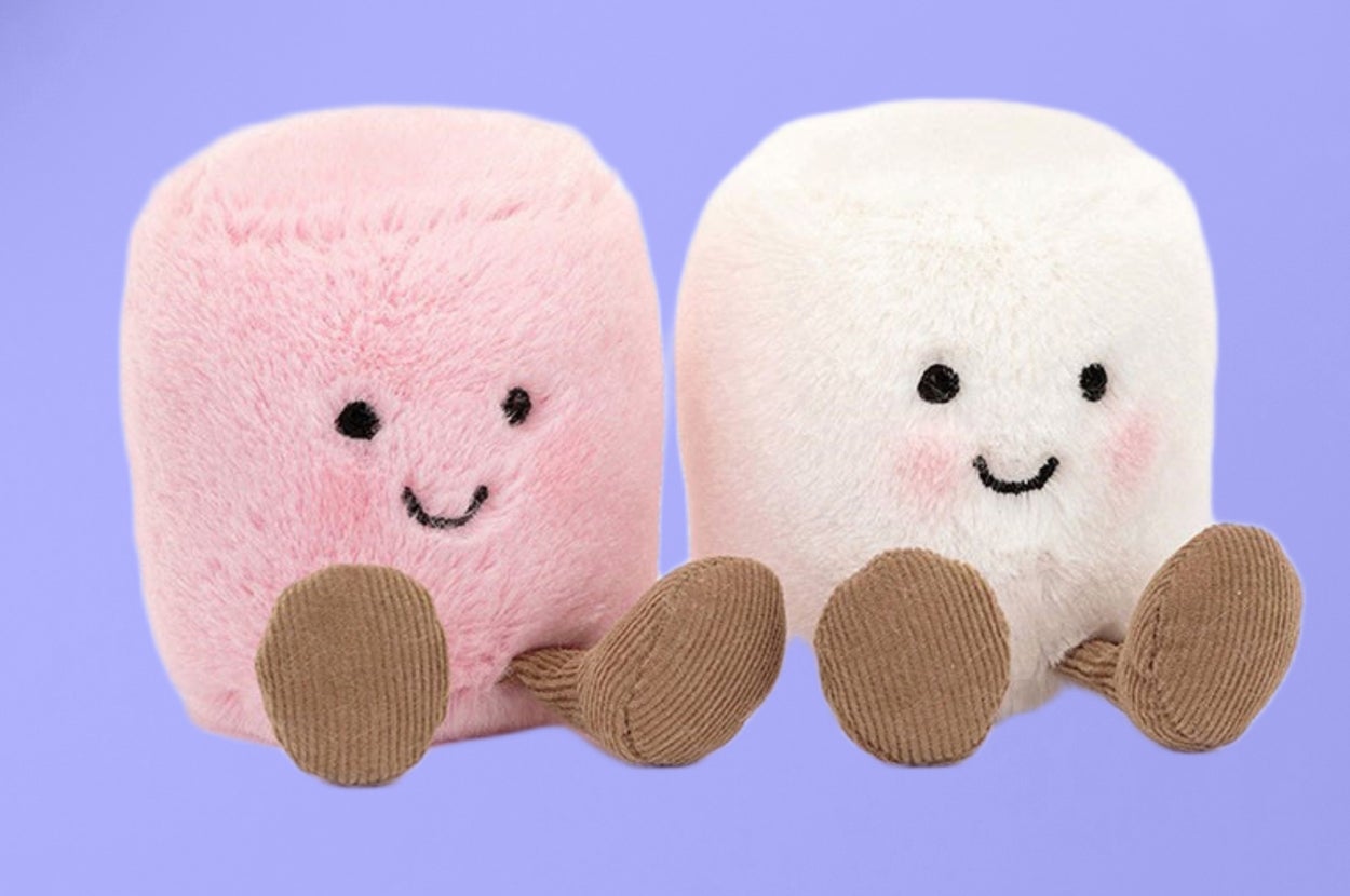 Two plush marshmallow toys with smiling faces and small feet are side by side on a plain background
