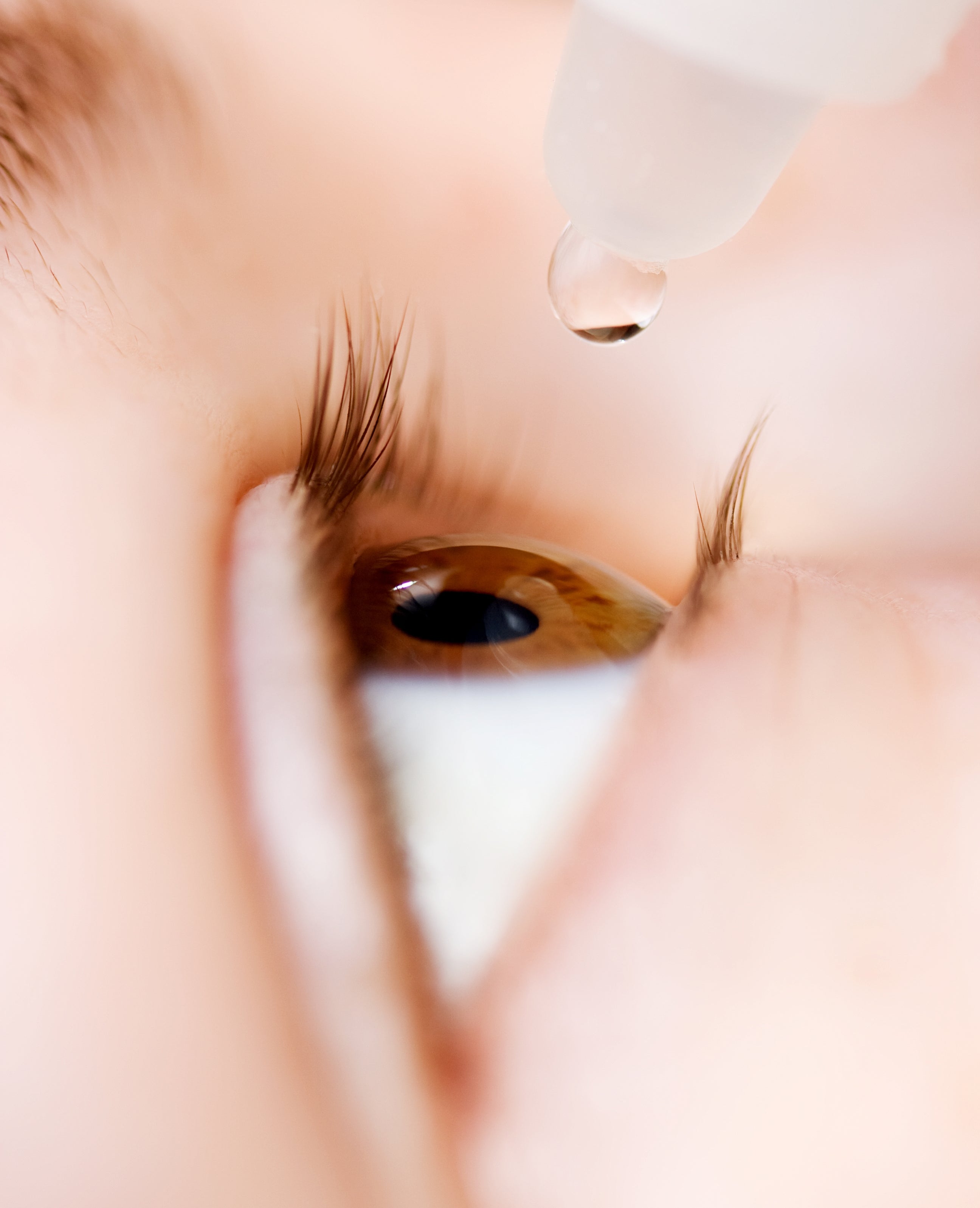 Nærbilde av et øye med en dropper som påfører øyedråper i det åpne øyet, og understreker omsorg og behandling