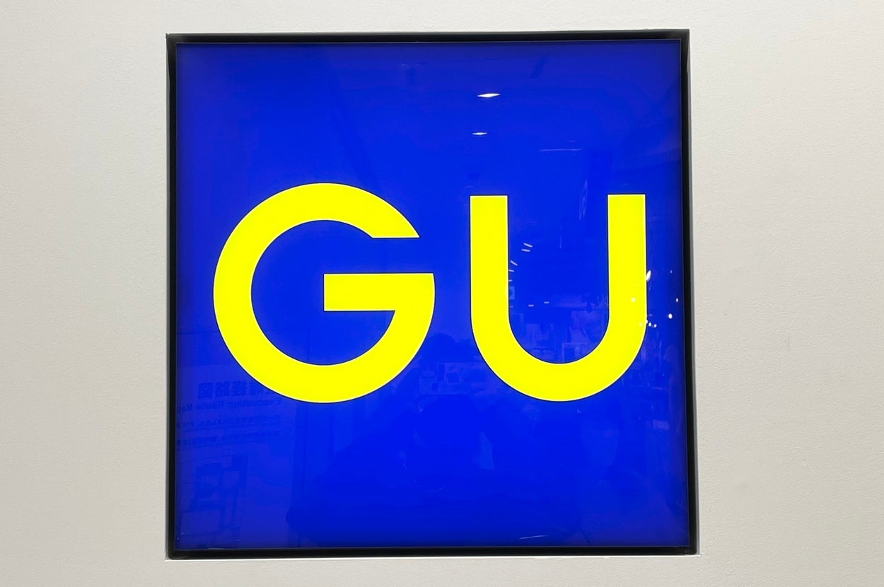Square sign with bold yellow "GU" letters on a contrasting background