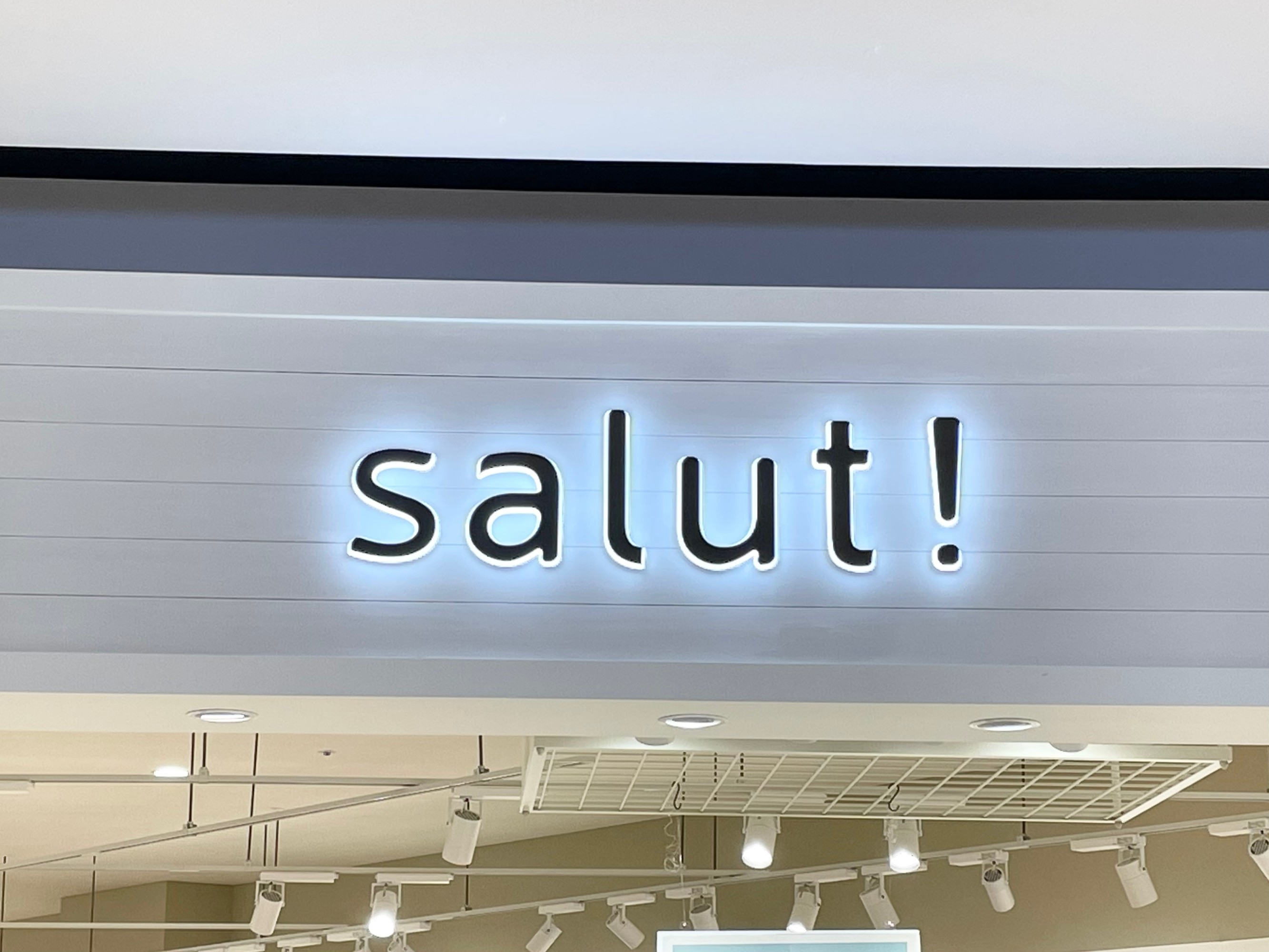 店舗の看板に「salut!」と書かれている。室内の照明が見える。