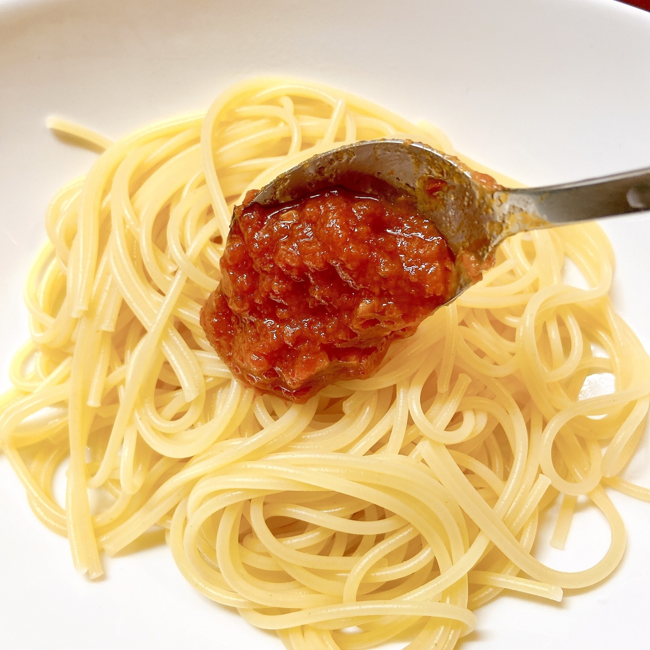 スパゲッティにトマトソースをかける様子。