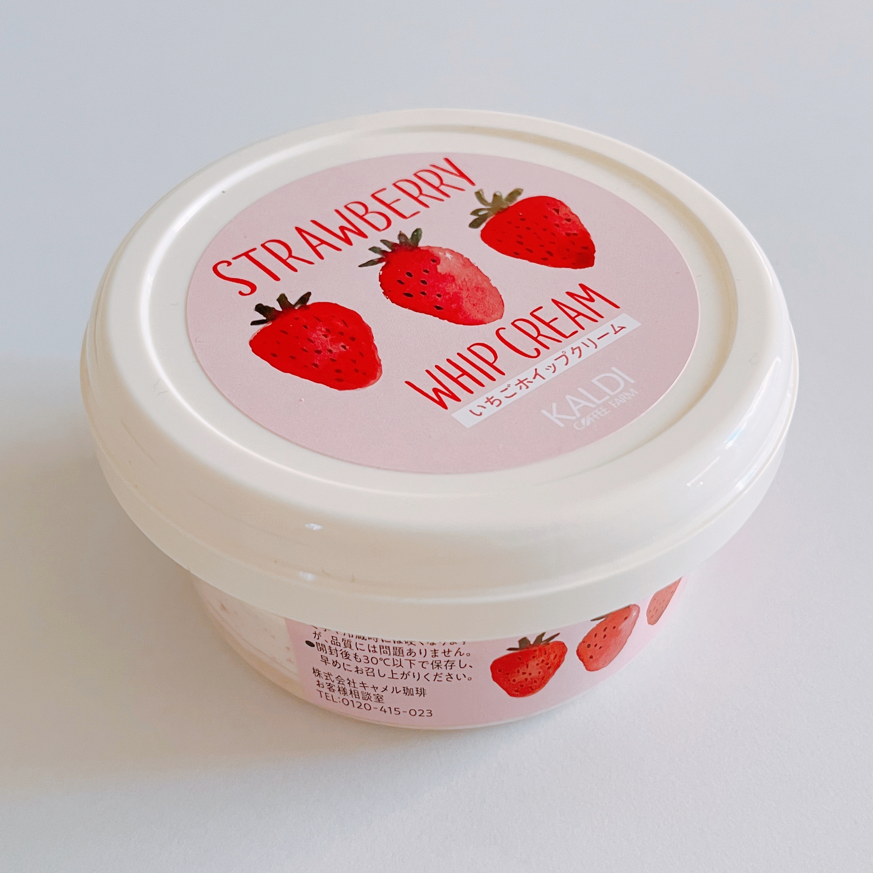 白いプラスチック容器に入ったストロベリー風味のホイップクリーム。ふたと側面にイチゴのイラスト付き。