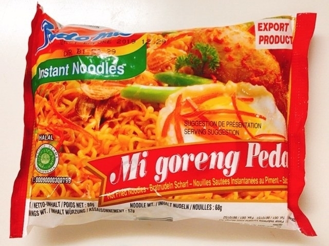インスタント麺のパッケージ、トッピング例付き。ミーゴレン・ペダスの表示。広告記事用の画像。