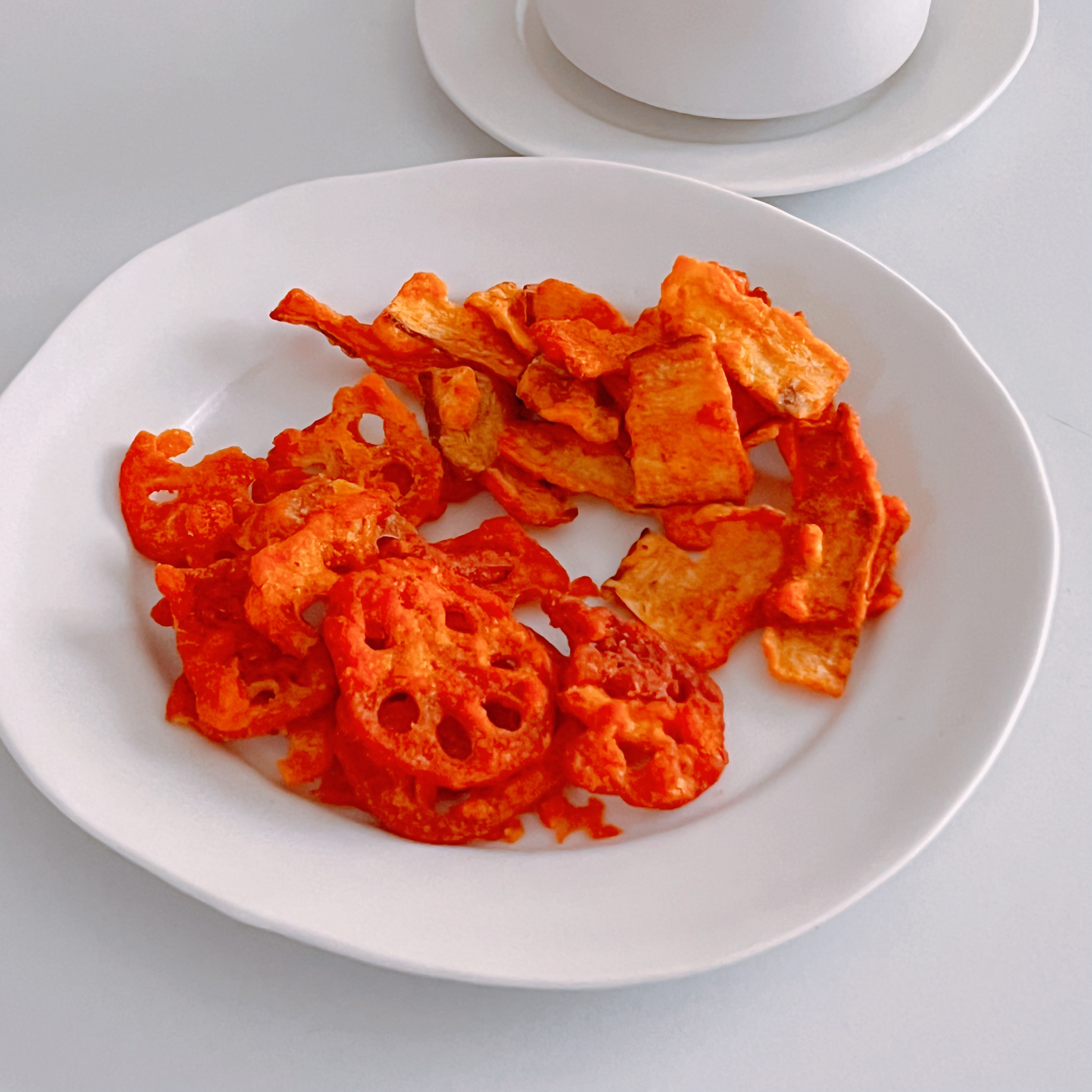 白い皿に盛られたレンコンやその他の野菜のチップスがテーブルに置かれている。
