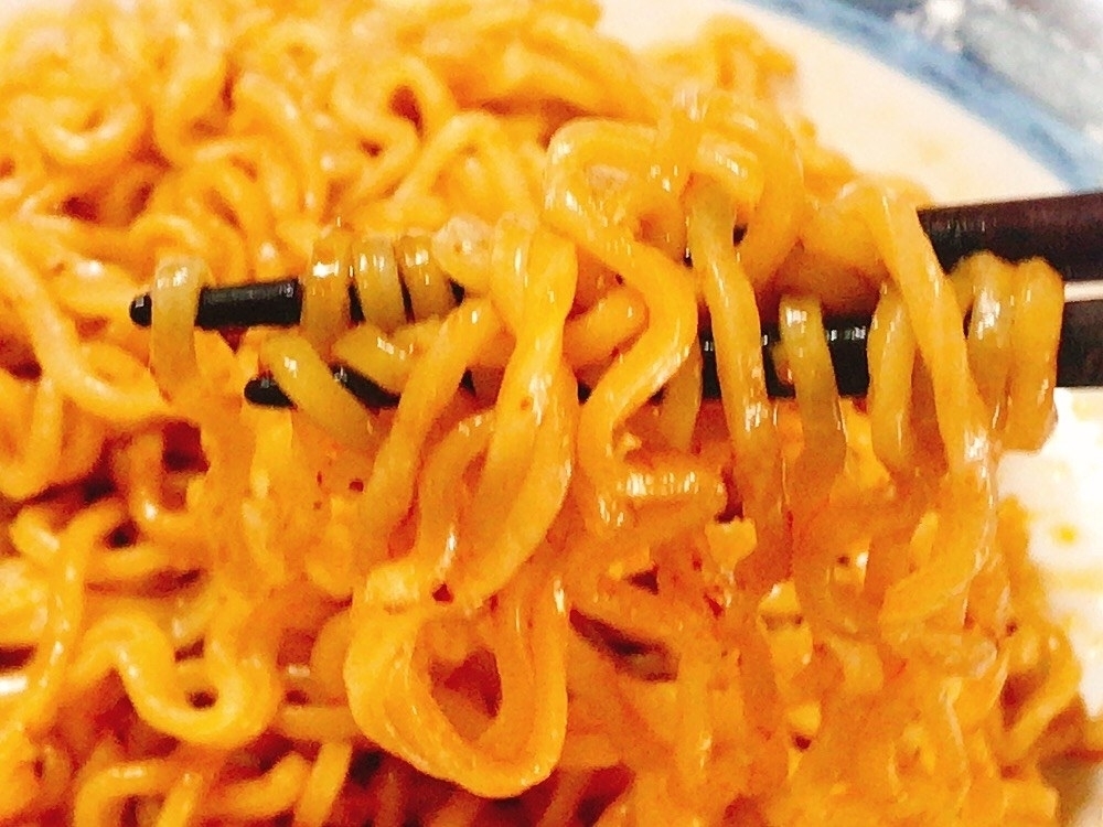箸で持ち上げられたインスタントラーメンのクローズアップ。