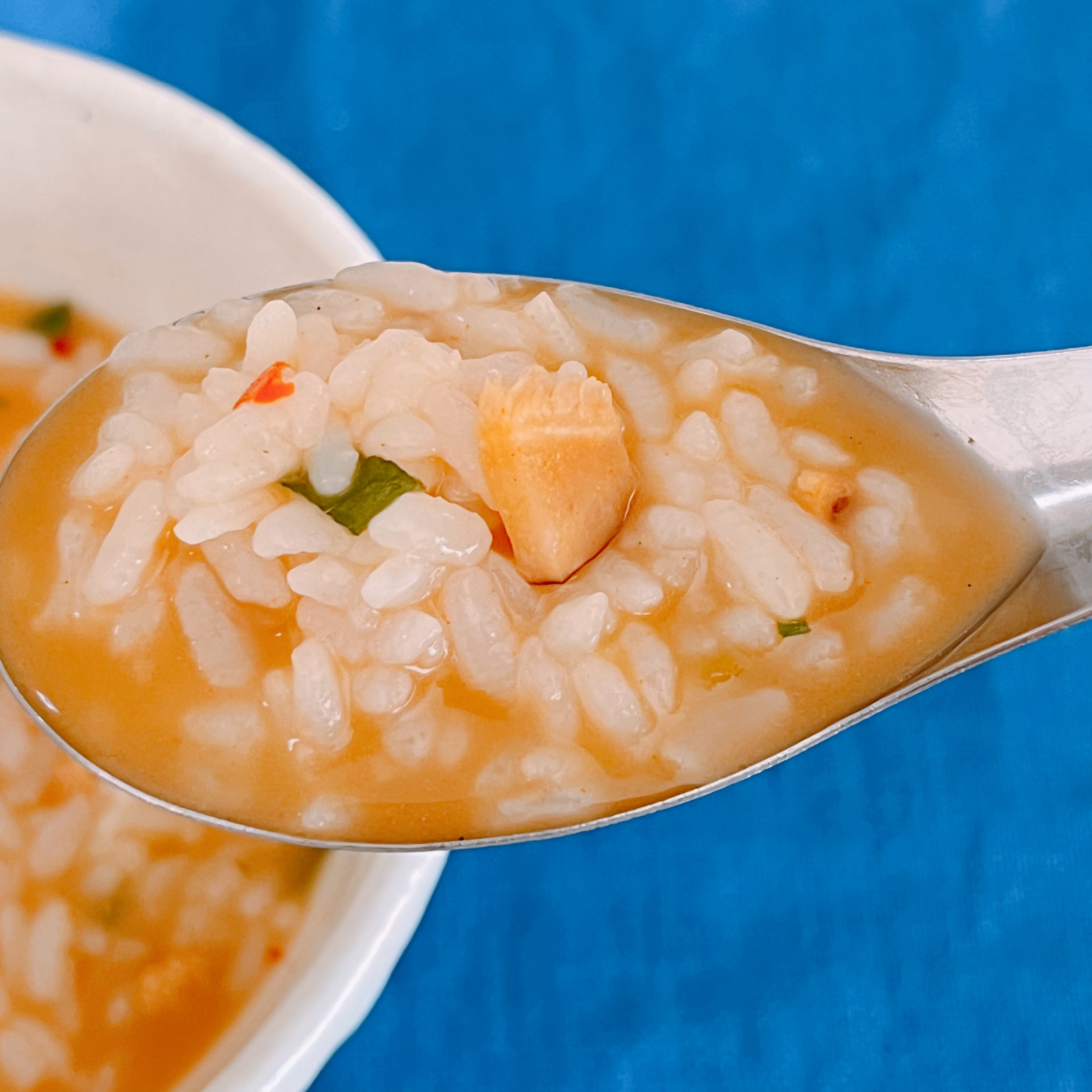 スプーンに盛られたお粥、チキンと野菜が見える。