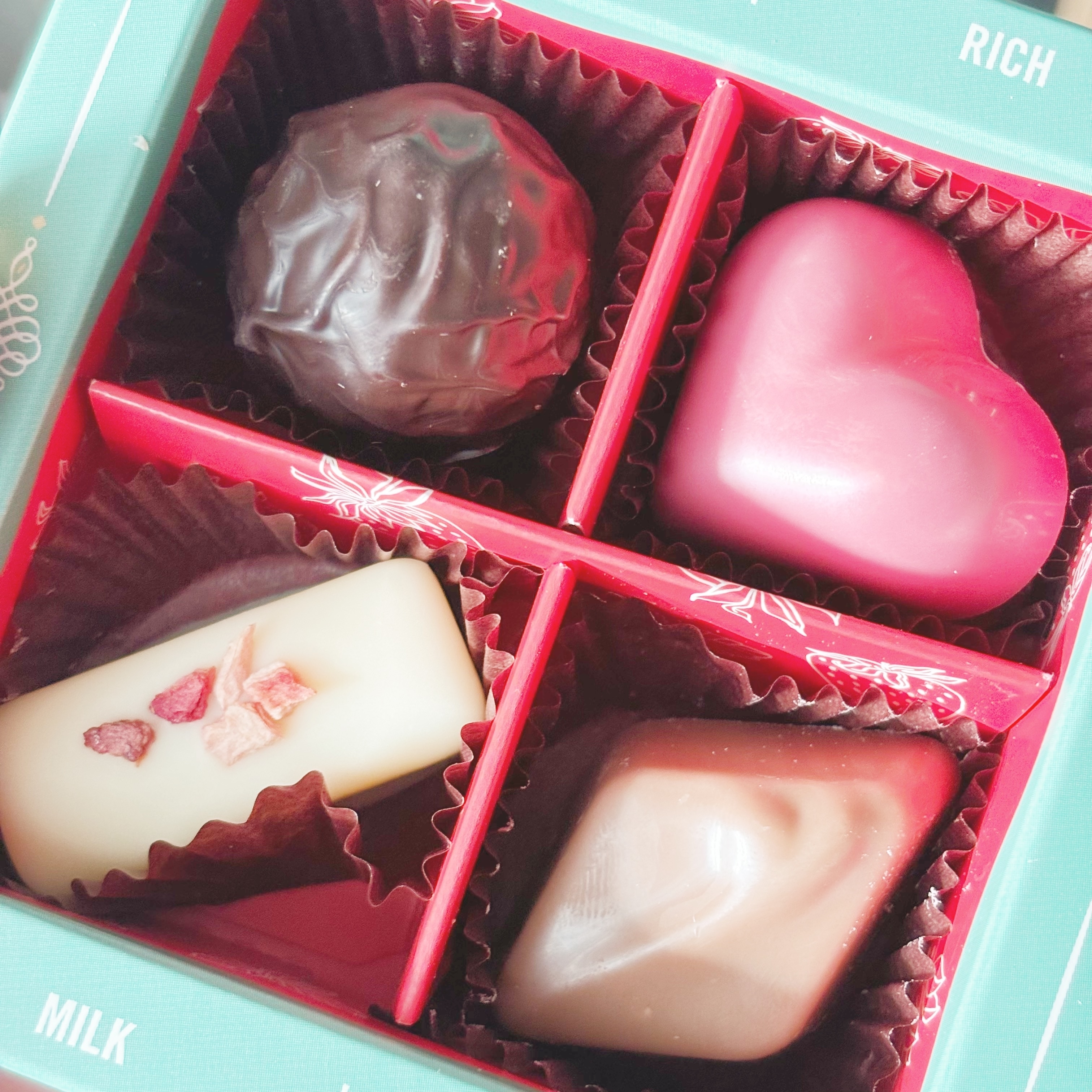 様々な形のチョコレートが4つ入ったボックス。ハート型やトリュフが見られる。