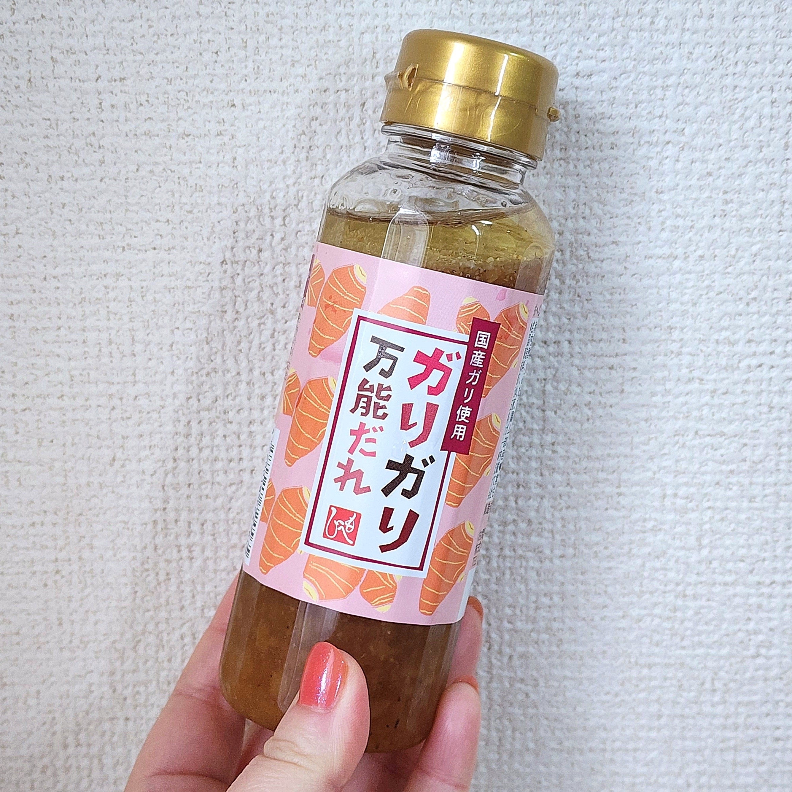 手に持たれた瓶入りの調味料。ラベルに「ガリガリ万能だれ」と書かれている。