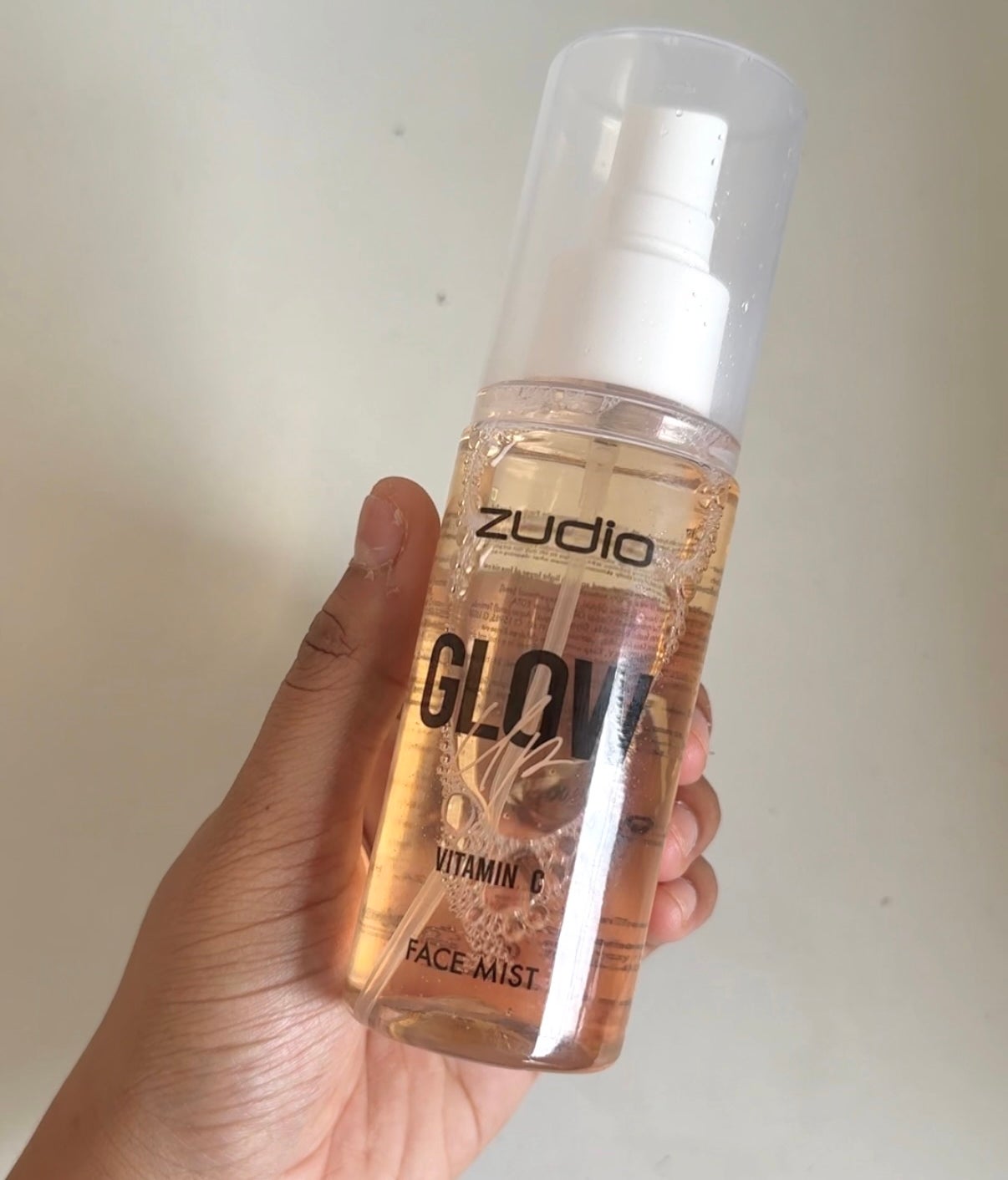 Hand holding a bottle of face mist labeled "Zudio Glow Vitamin C Face Mist."