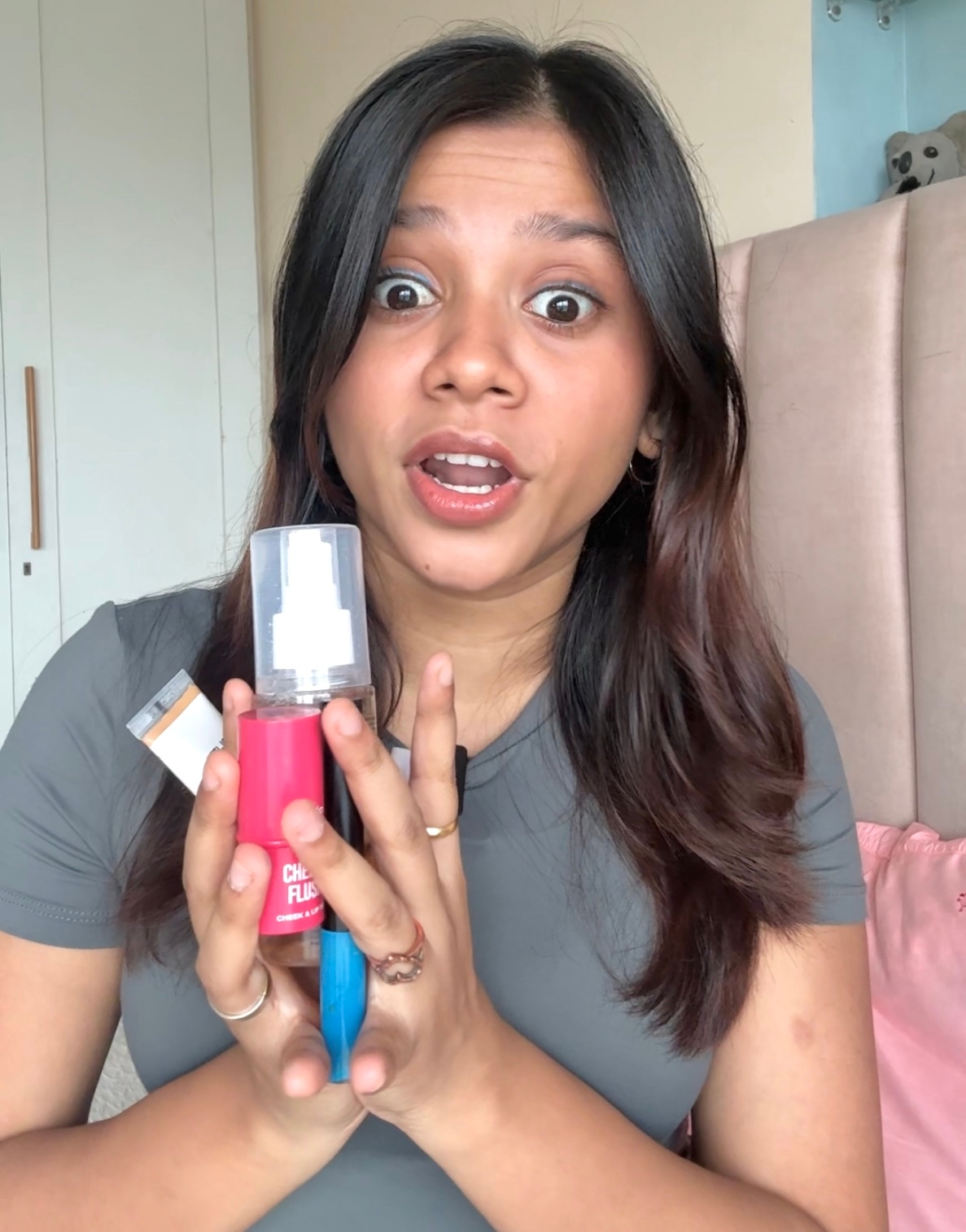 A person with an surprised expression holding a skincare product