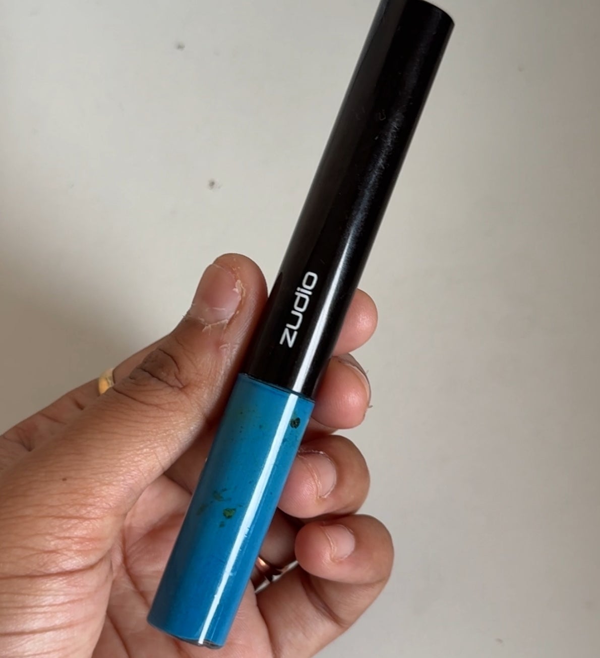 Hand holding a black and blue liquid eyeliner pen