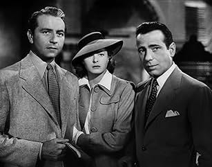 Three people in classic 1940s attire, including a woman with a hat. They appear serious, suggesting a dramatic or noir film scene