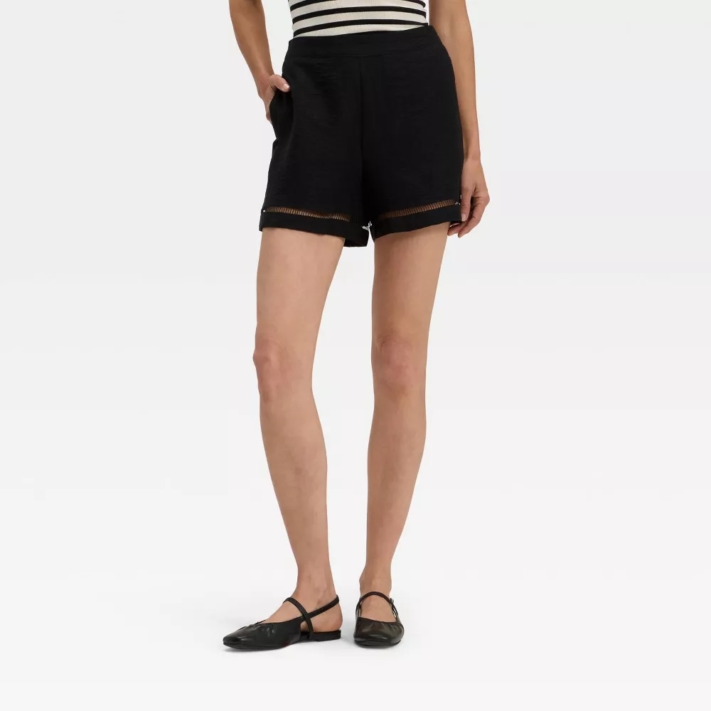 Person wearing striped top, black lace-trimmed shorts, and black flats. Image used for shopping context
