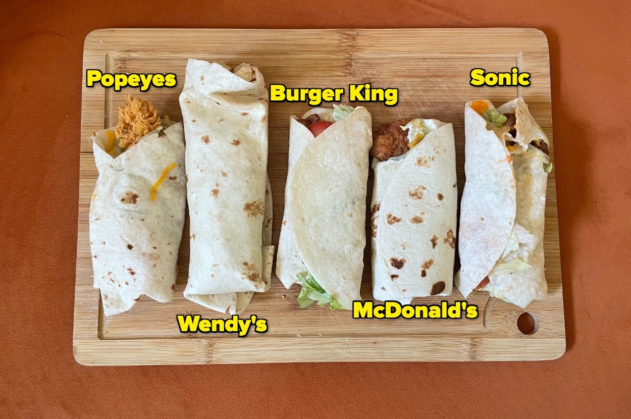 Five different fast-food wraps from Popeyes, Wendy's, Burger King, McDonald's, and Sonic arranged on a wooden board