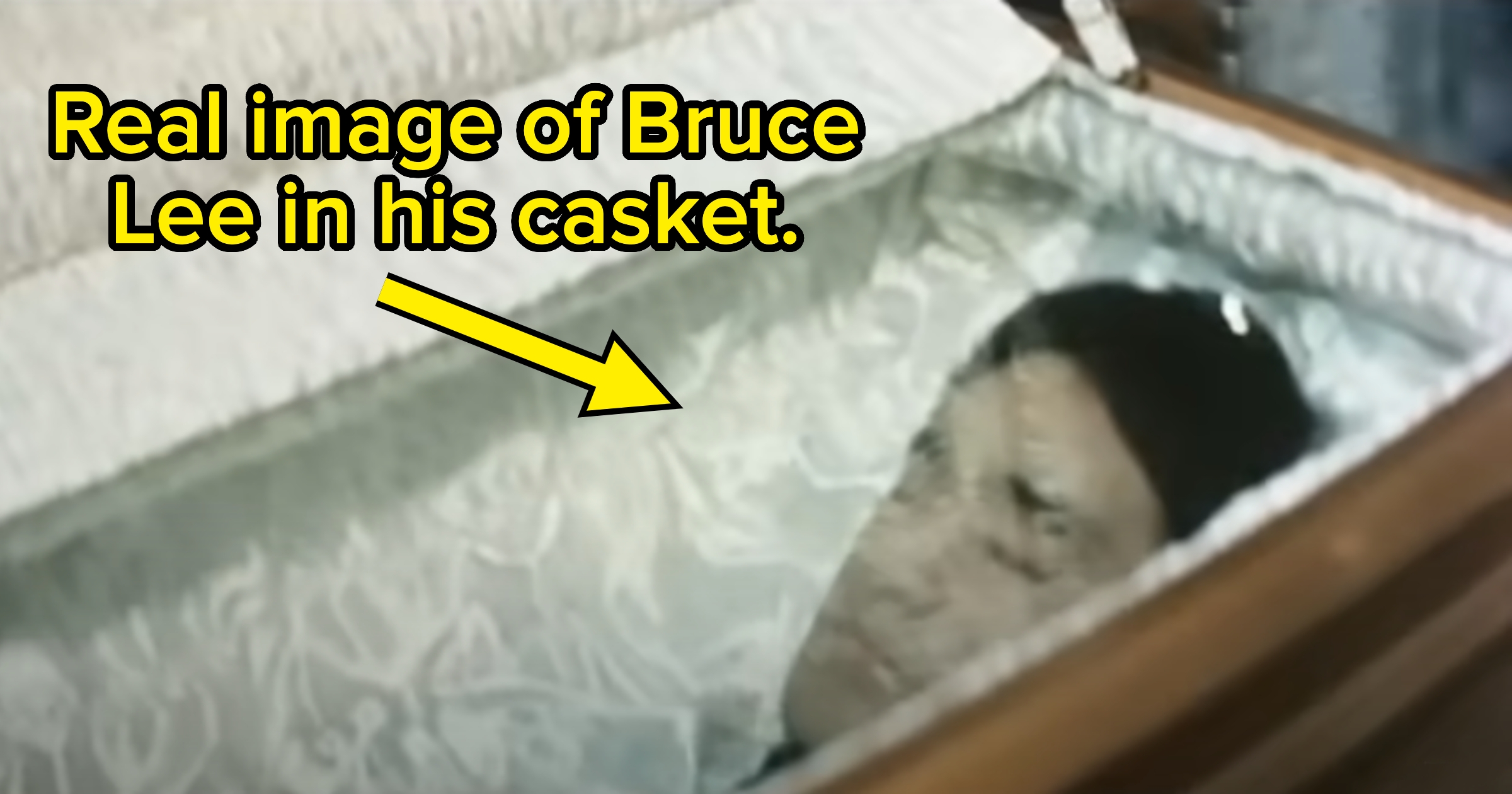 Man lying in an open casket with a satin lining; text reads, "Real image of Bruce Lee in his casket."